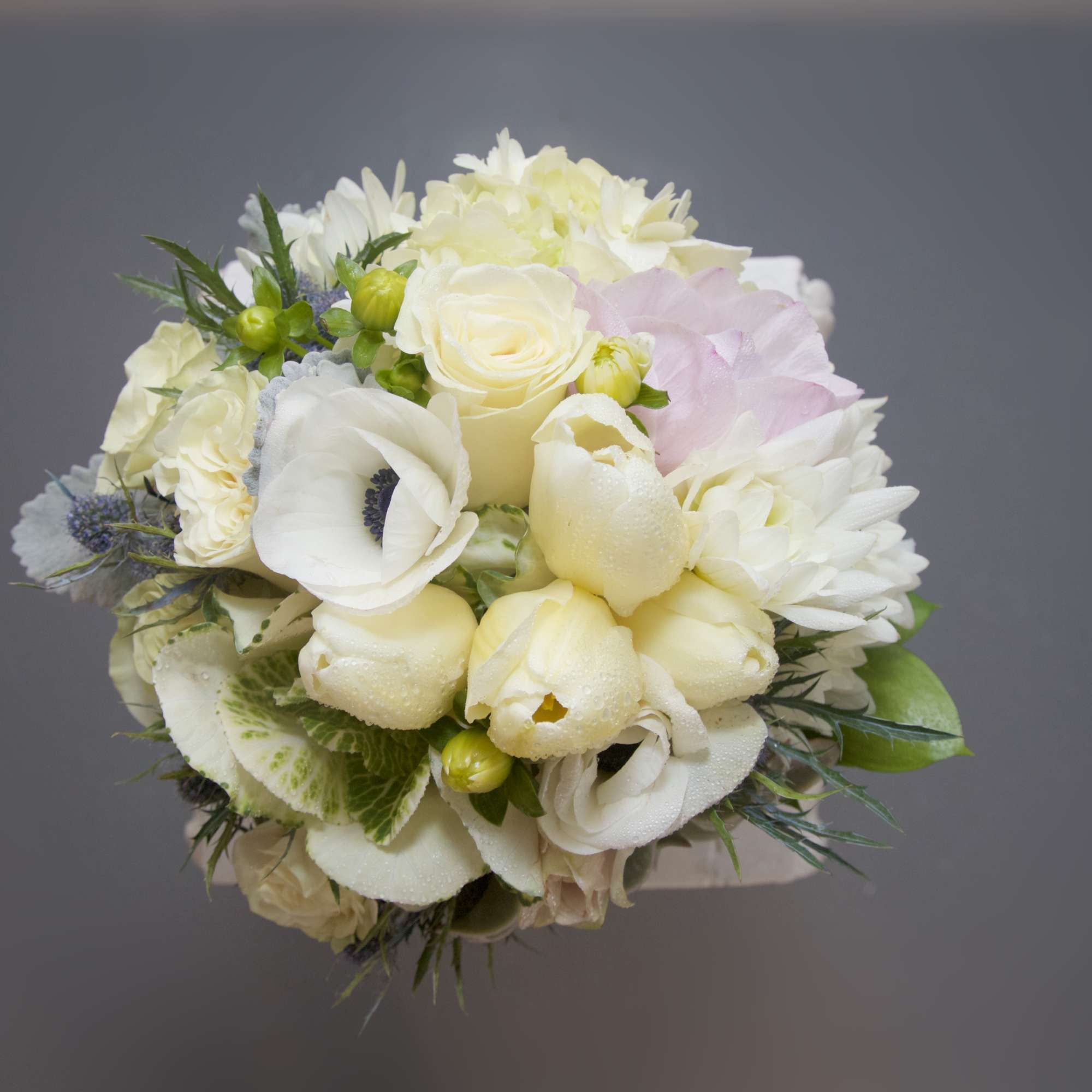 A refreshing arrangement of Snow White Roses and Lilies, frosty succulents framed