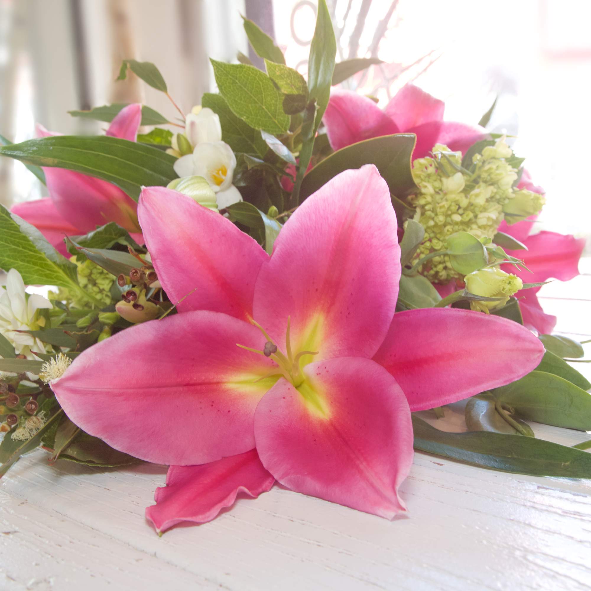 Hug your Darling Dearest with this wrapped bouquet of Lilies, Magnolia Greens