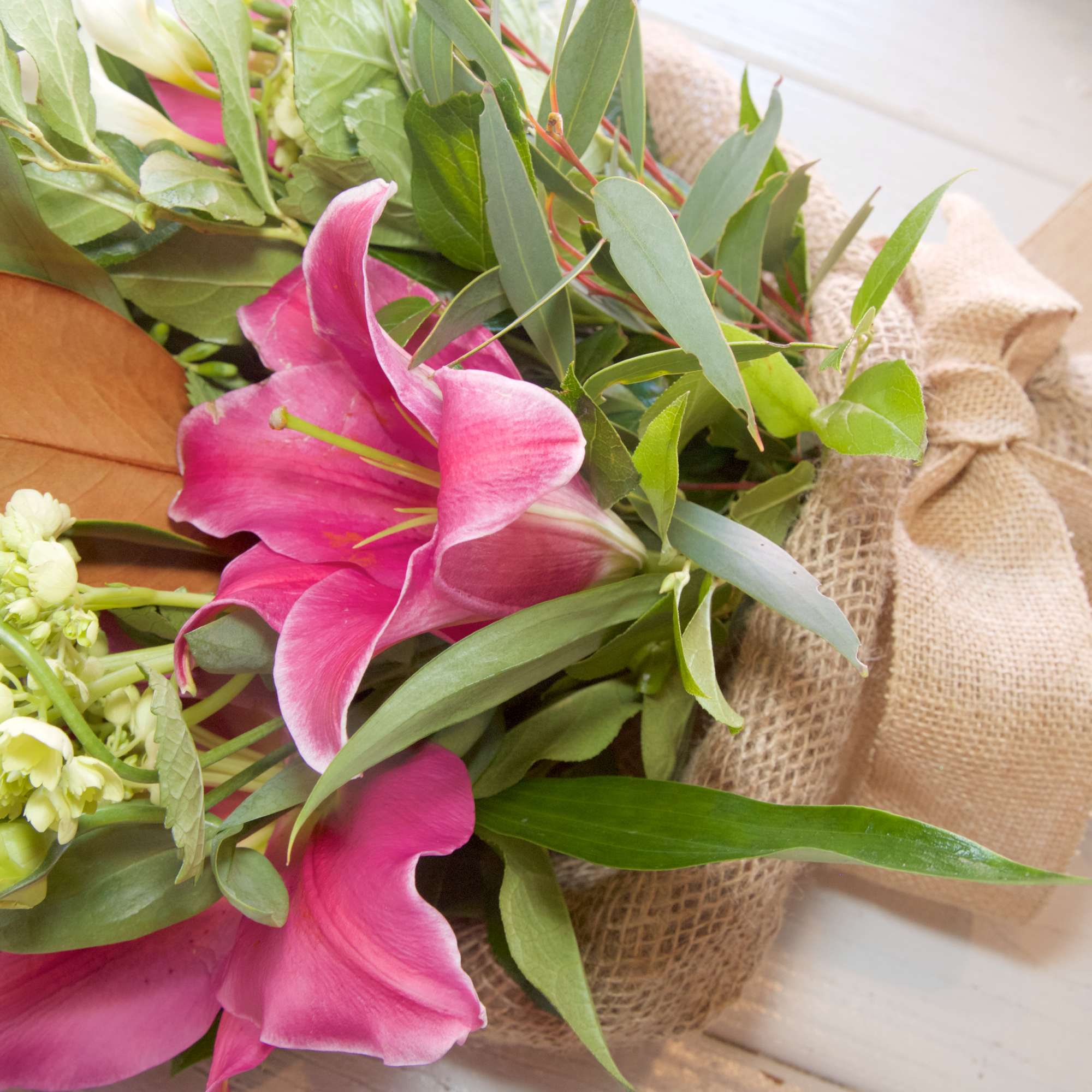 Hug your Darling Dearest with this wrapped bouquet of Lilies, Magnolia Greens