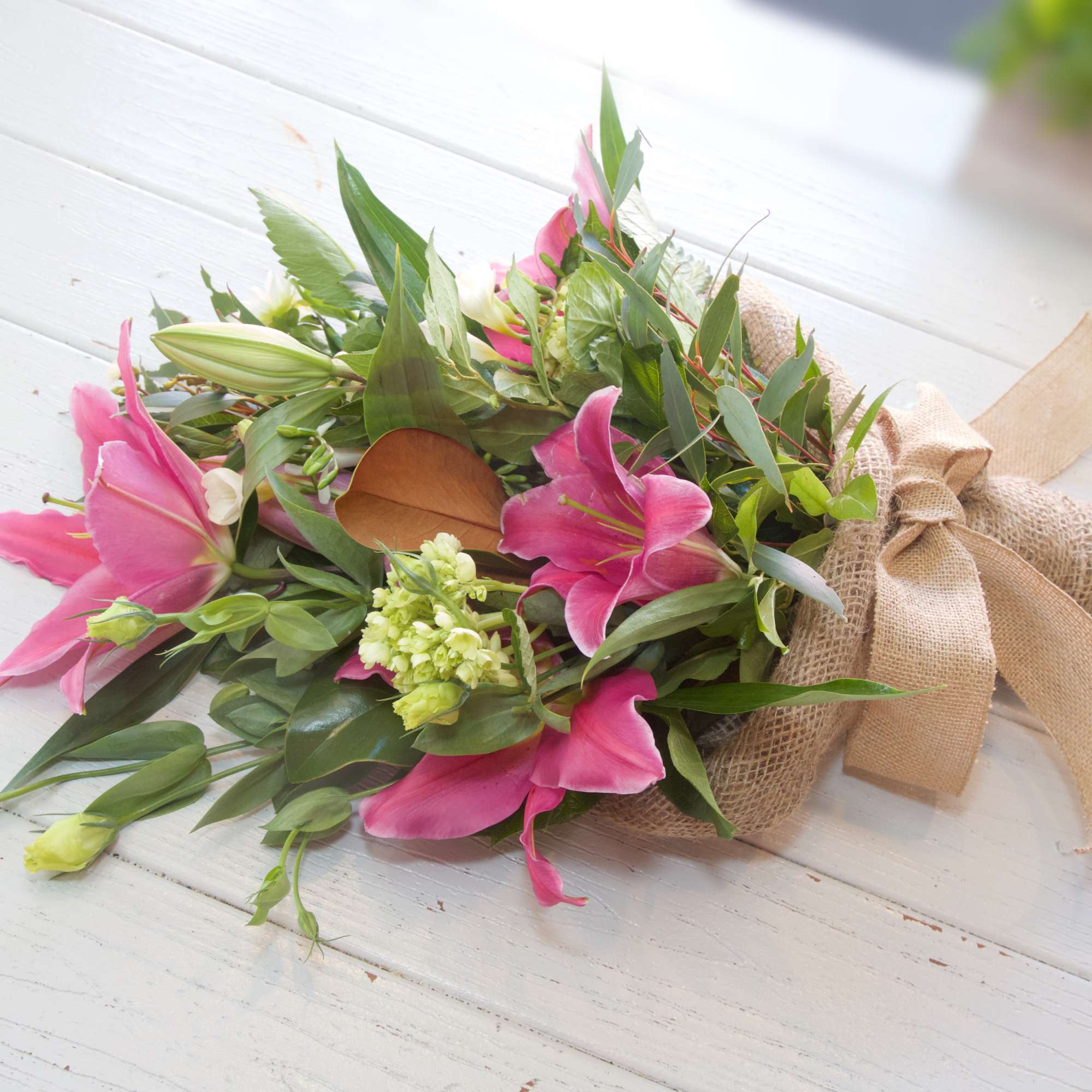 Hug your Darling Dearest with this wrapped bouquet of Lilies, Magnolia Greens