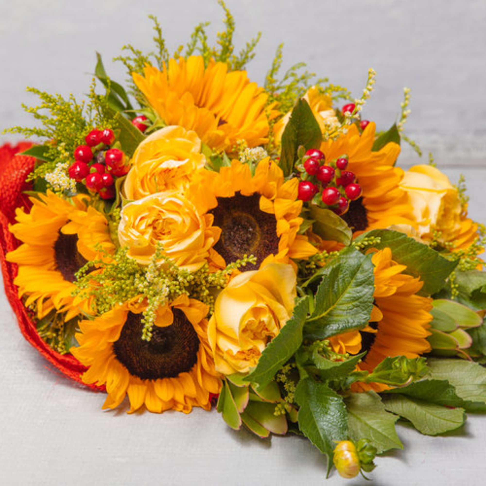 This red burlap wrapped bouquet features delightful Sunflowers, pale yellow Roses, red