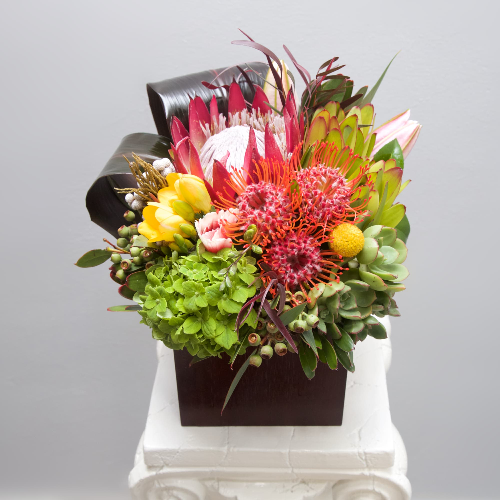 This tropical blend of hot pink blooms, artistic banana leaves and succulents