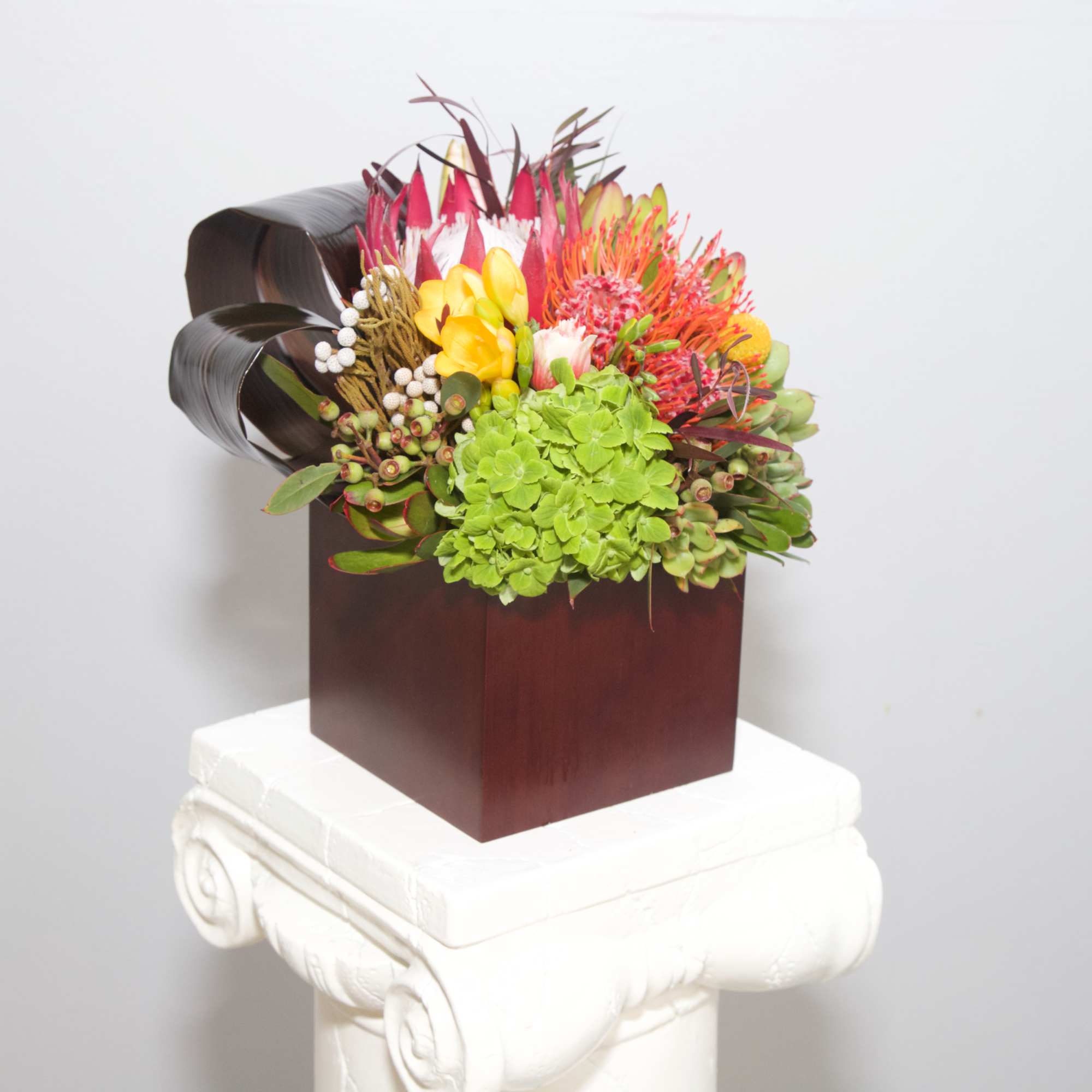 This tropical blend of hot pink blooms, artistic banana leaves and succulents