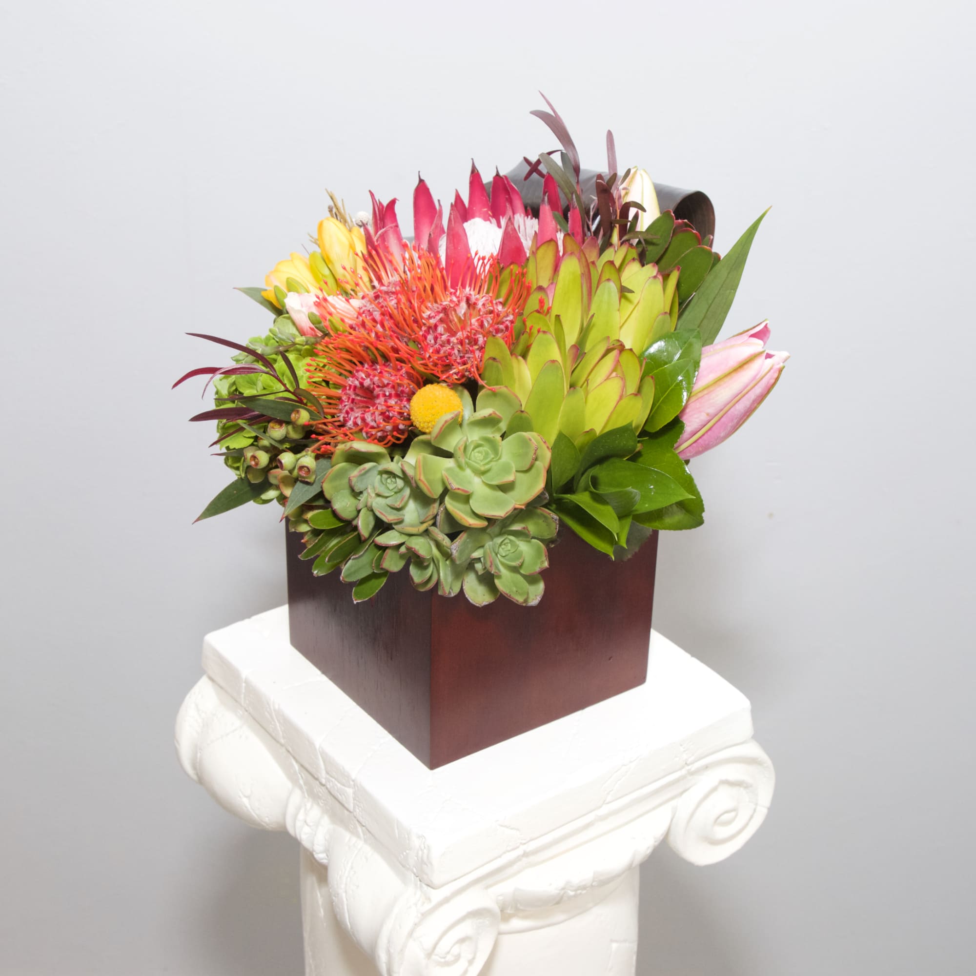 This tropical blend of hot pink blooms, artistic banana leaves and succulents