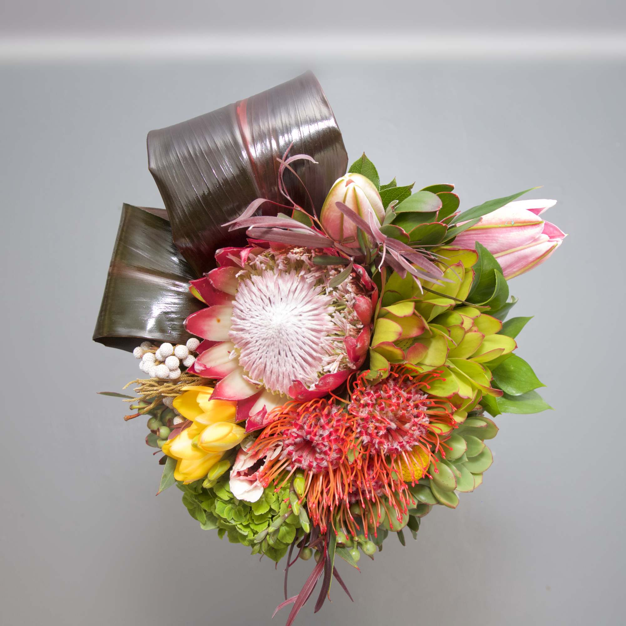 This tropical blend of hot pink blooms, artistic banana leaves and succulents