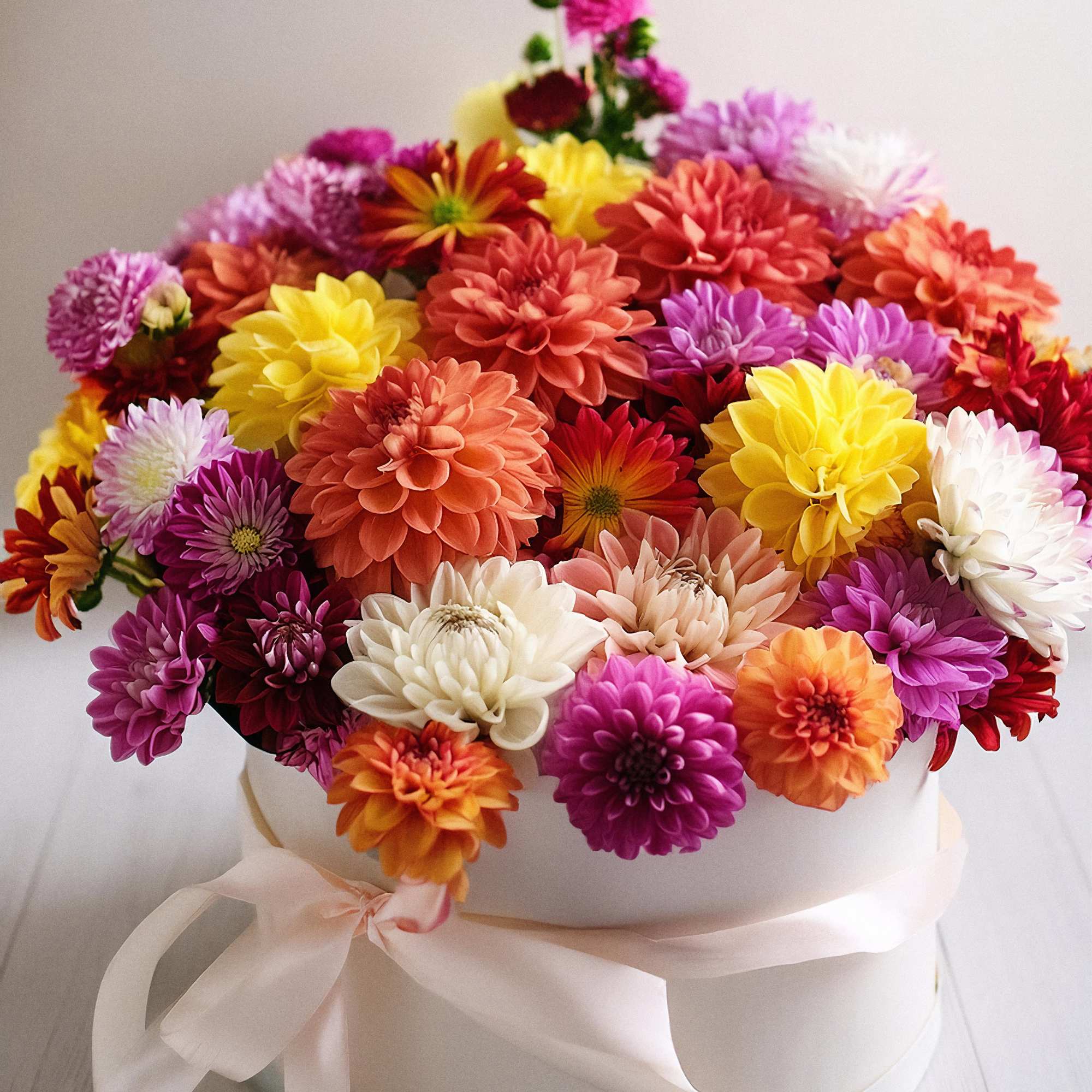 Vibrant floral arrangement, beautifully displayed in a white hatbox. This stunning mix