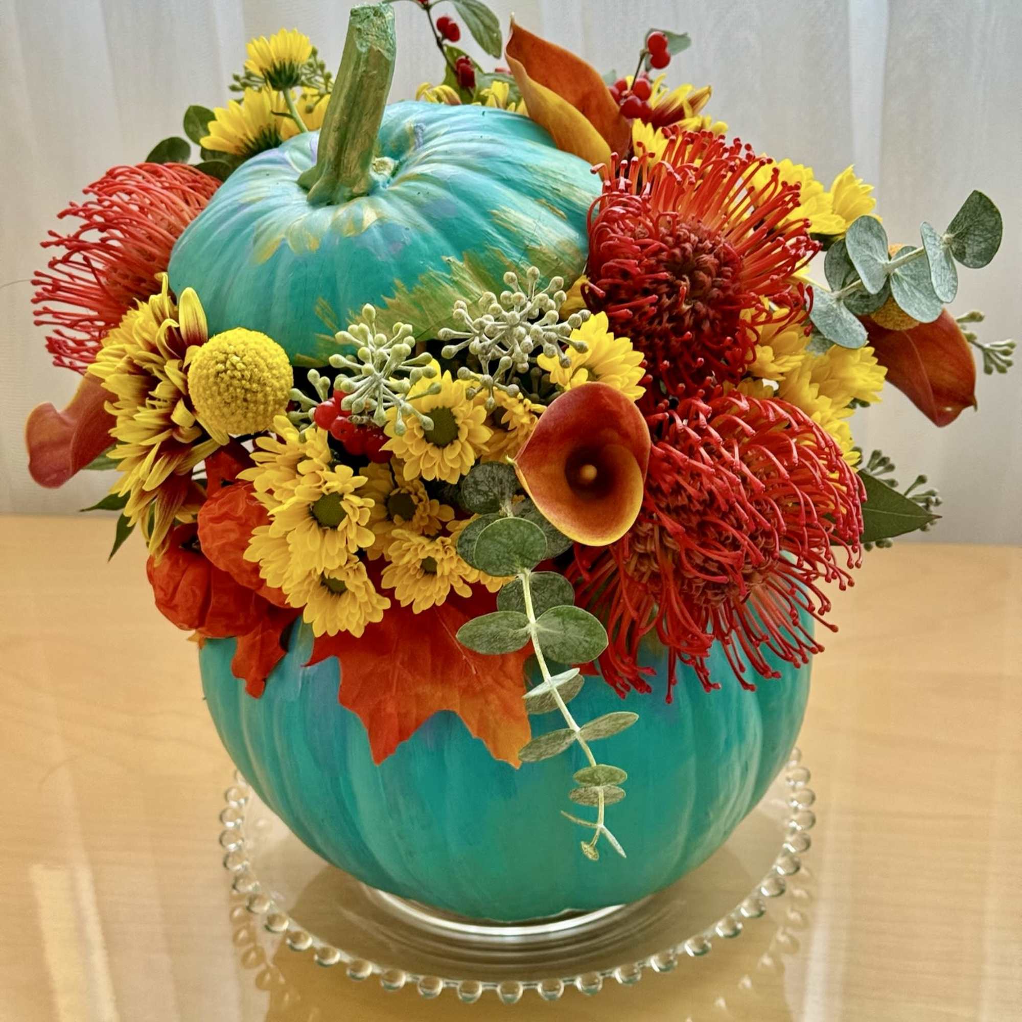 This vibrant and playful fall arrangement is designed in a stunning turquoise