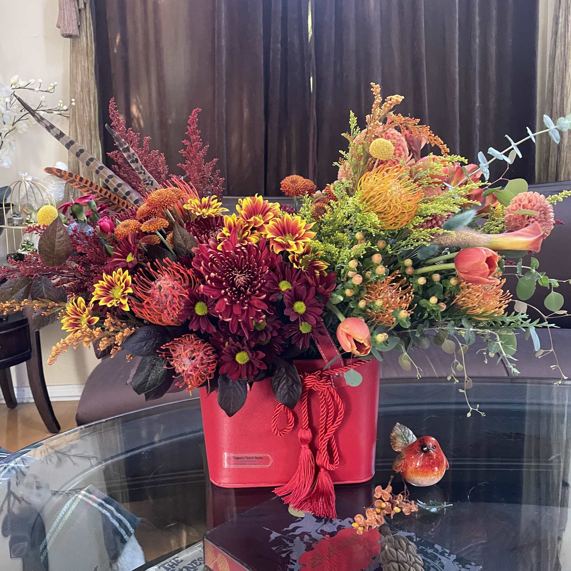 A floral arrangement in a red purse with tassels is undeniably a