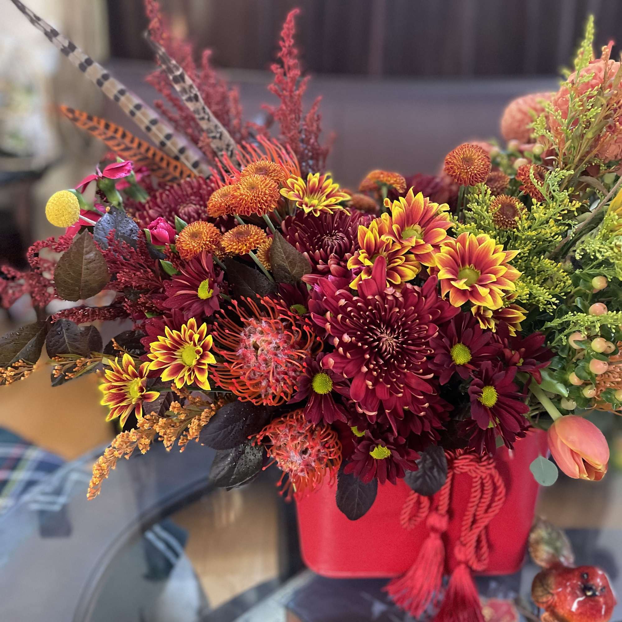 A floral arrangement in a red purse with tassels is undeniably a