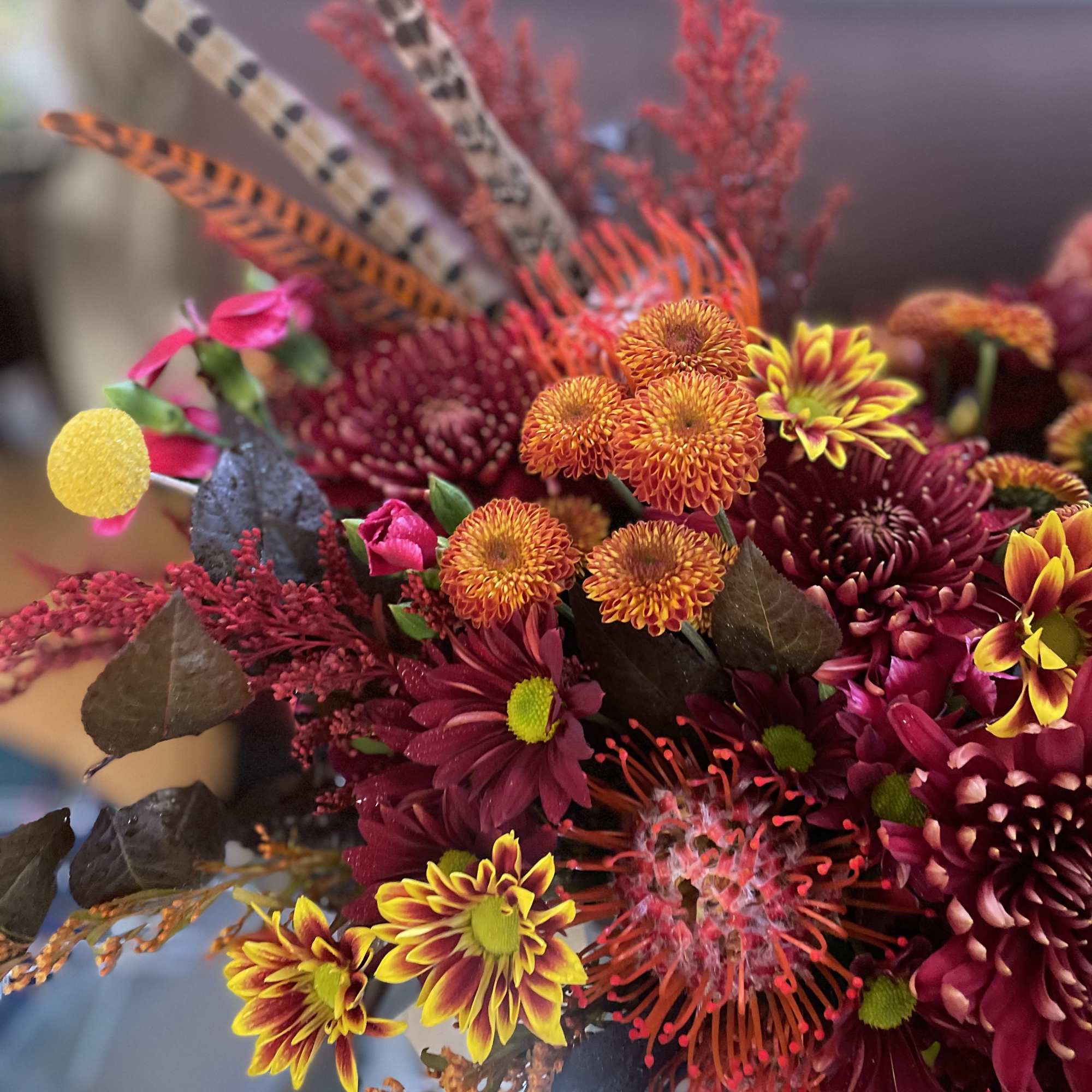 A floral arrangement in a red purse with tassels is undeniably a