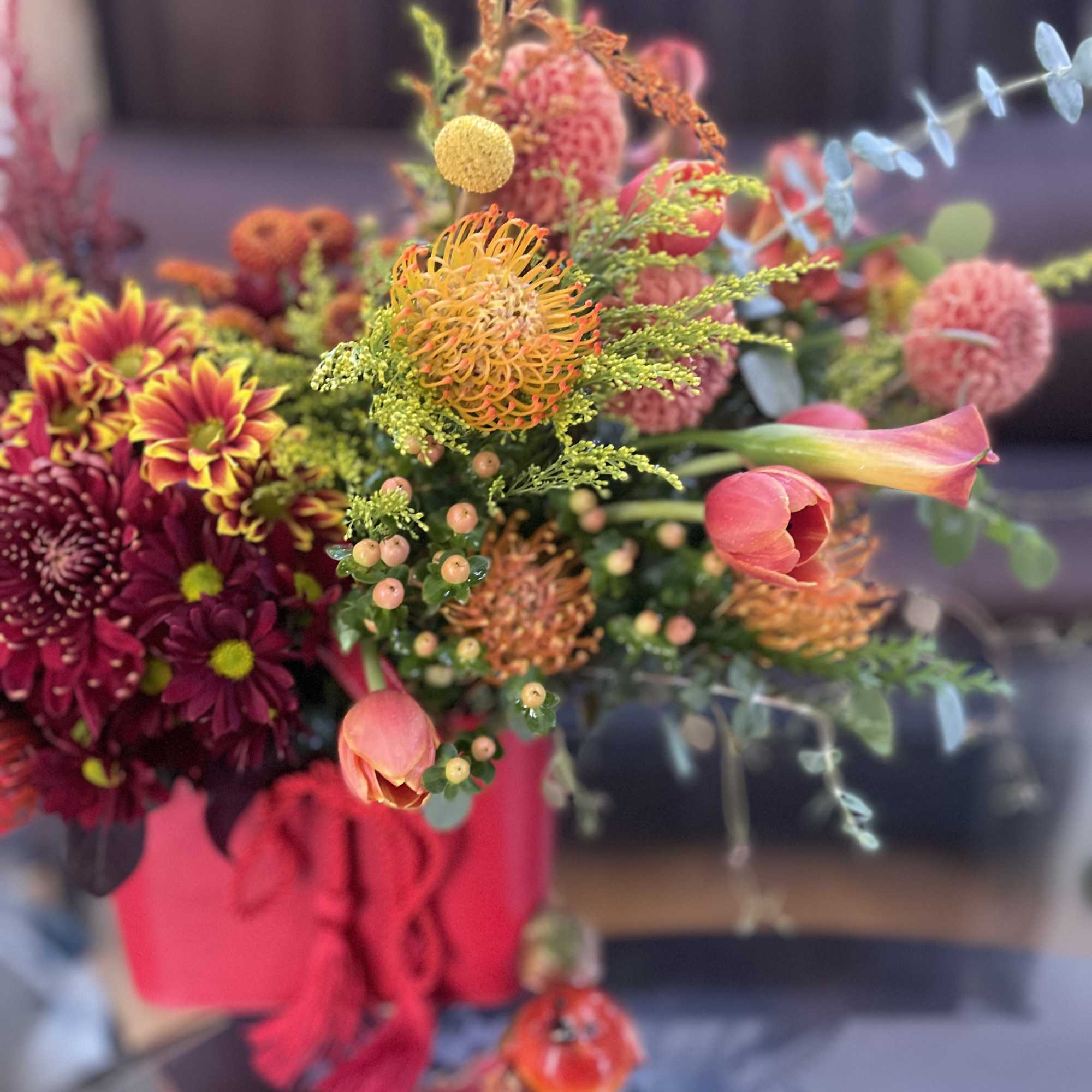 A floral arrangement in a red purse with tassels is undeniably a