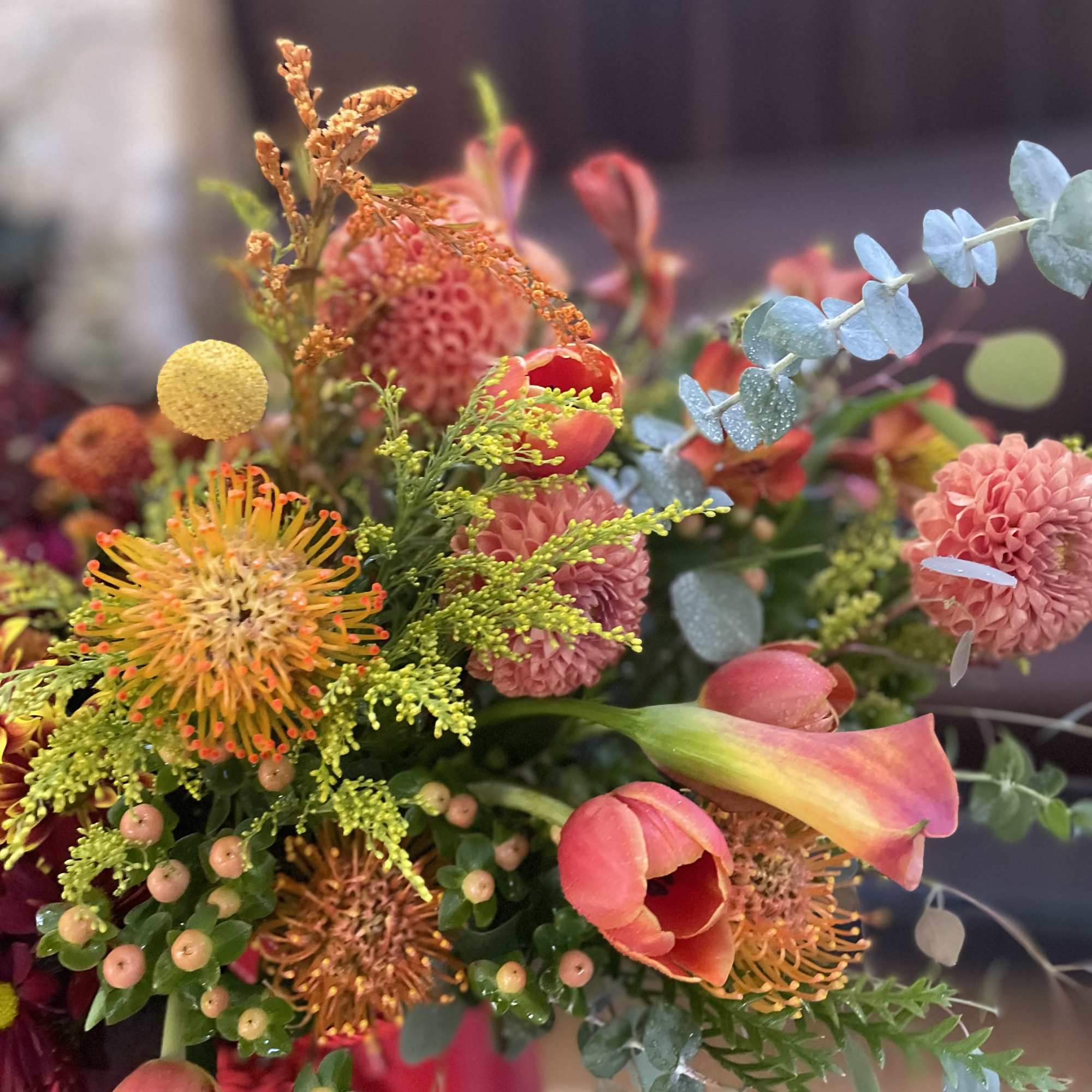 A floral arrangement in a red purse with tassels is undeniably a