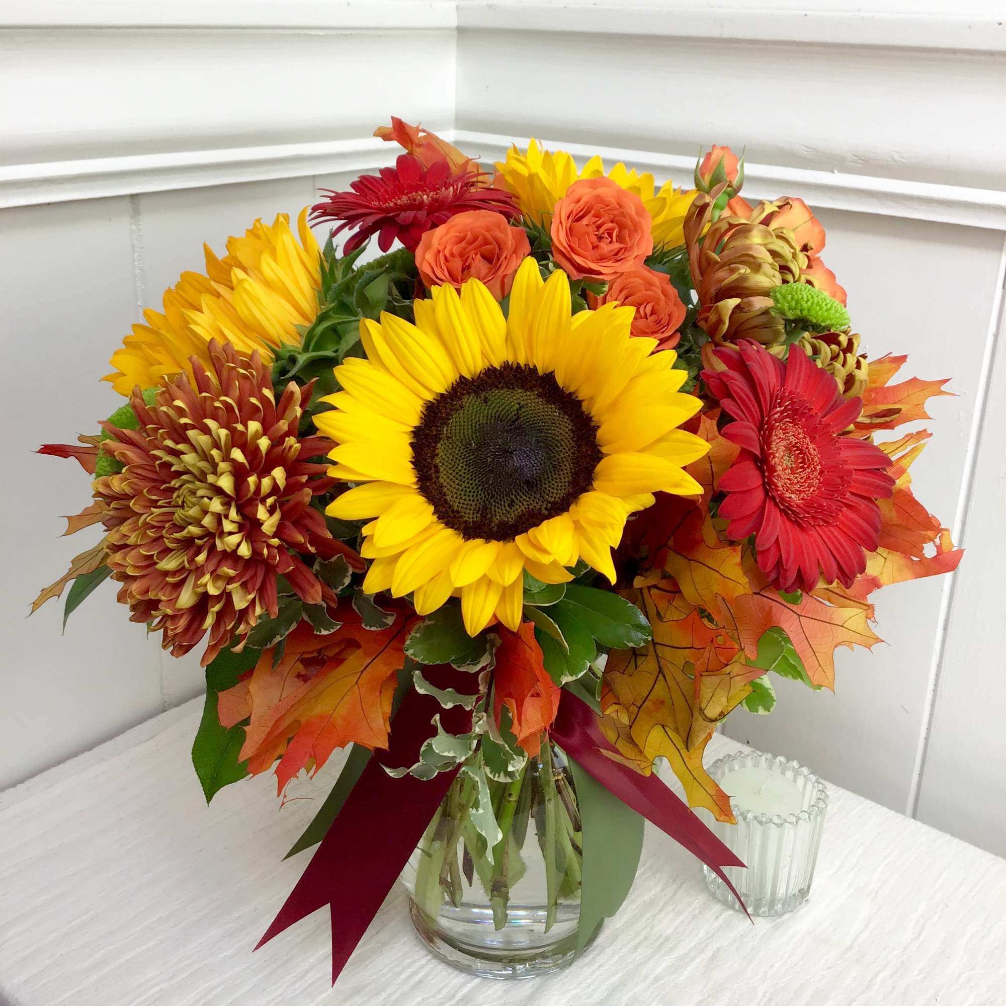 Bright flowers in red, orange, and gold tones accented with sunflowers. Finished