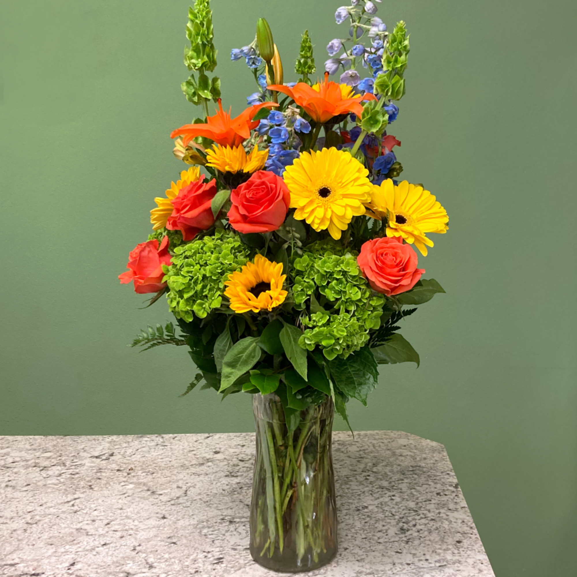 A tall and vibrant mixed arrangement showcasing bright, cheerful shades of orange
