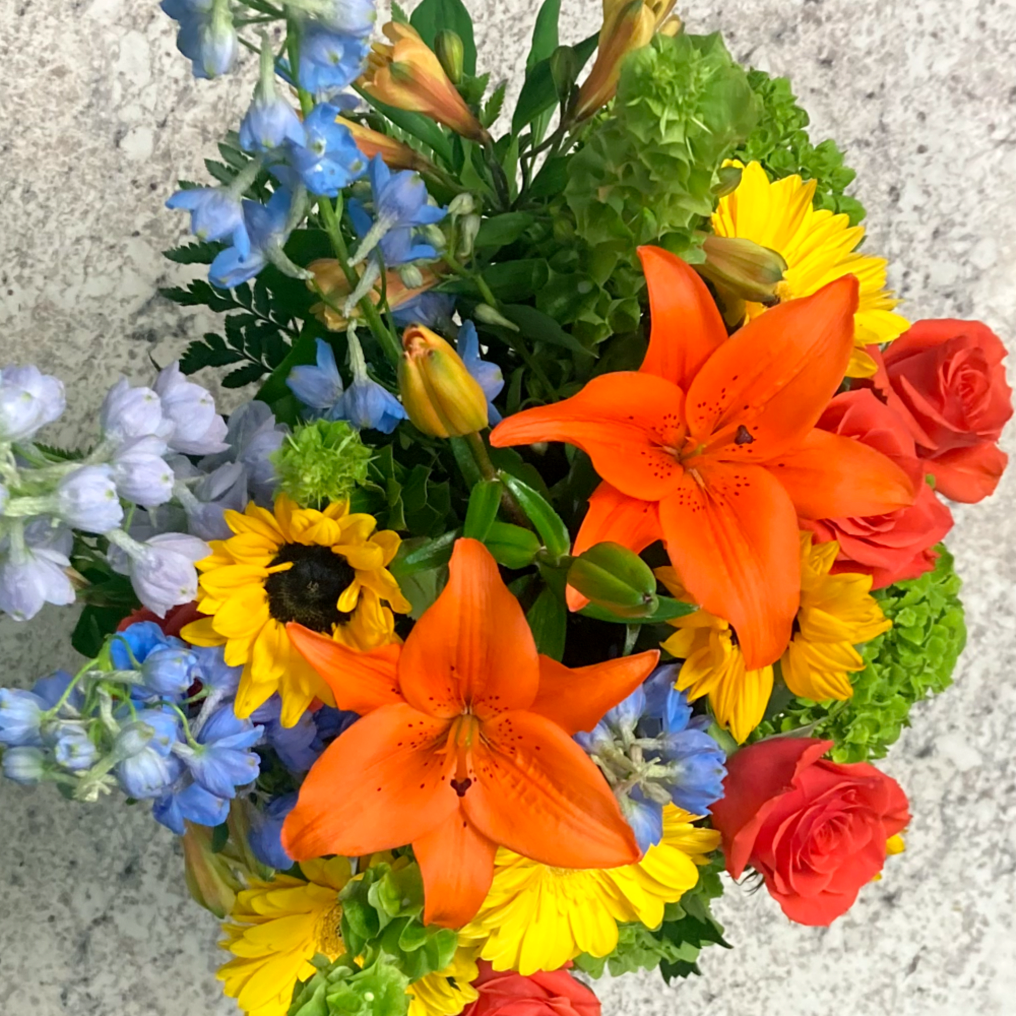 A tall and vibrant mixed arrangement showcasing bright, cheerful shades of orange