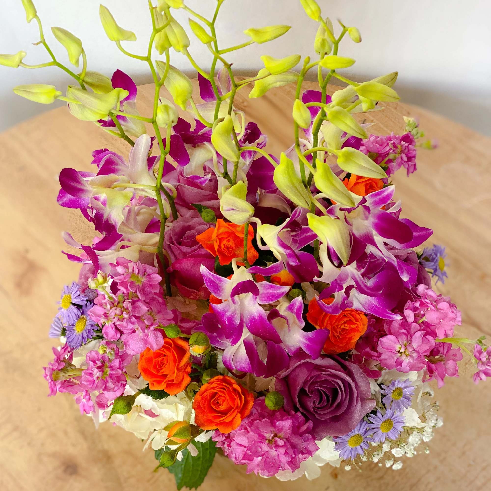 A bouquet with coral roses, purple dendrobium orchids, hydrangeas and fragrant lavender