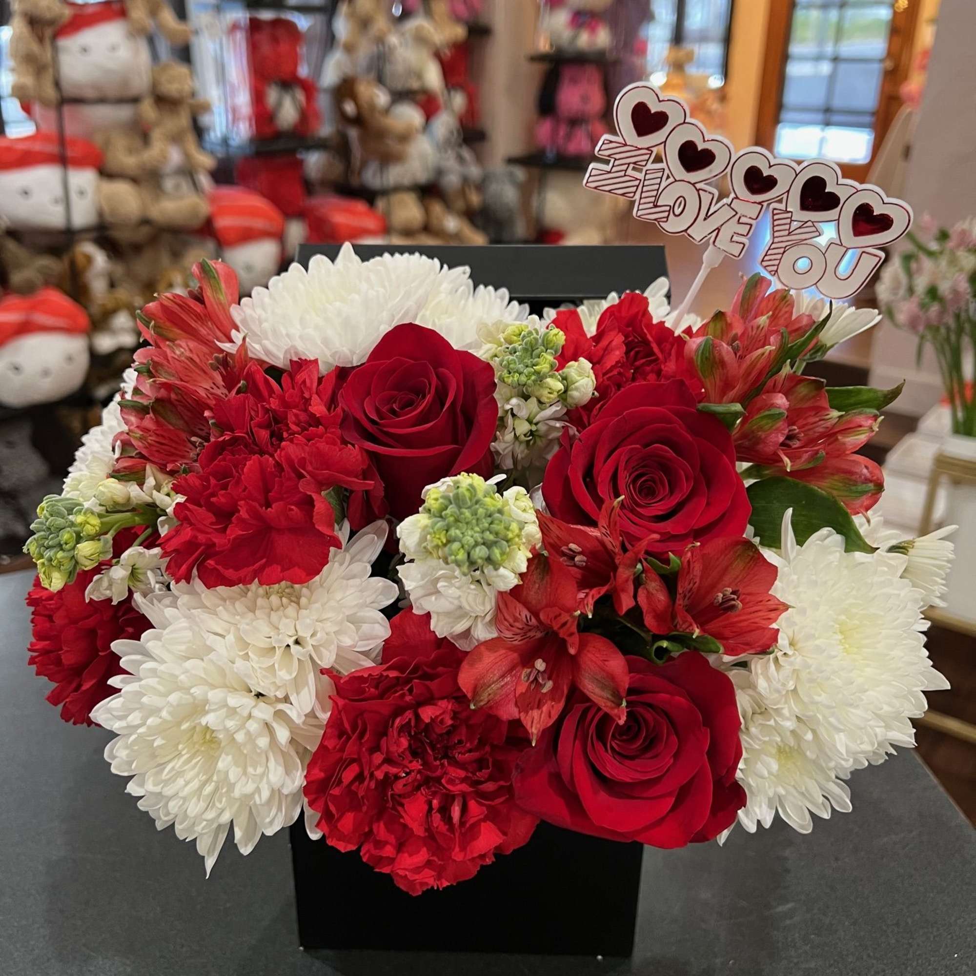 Red roses, red carnation, red alstromerias, white poms, and white stocks are