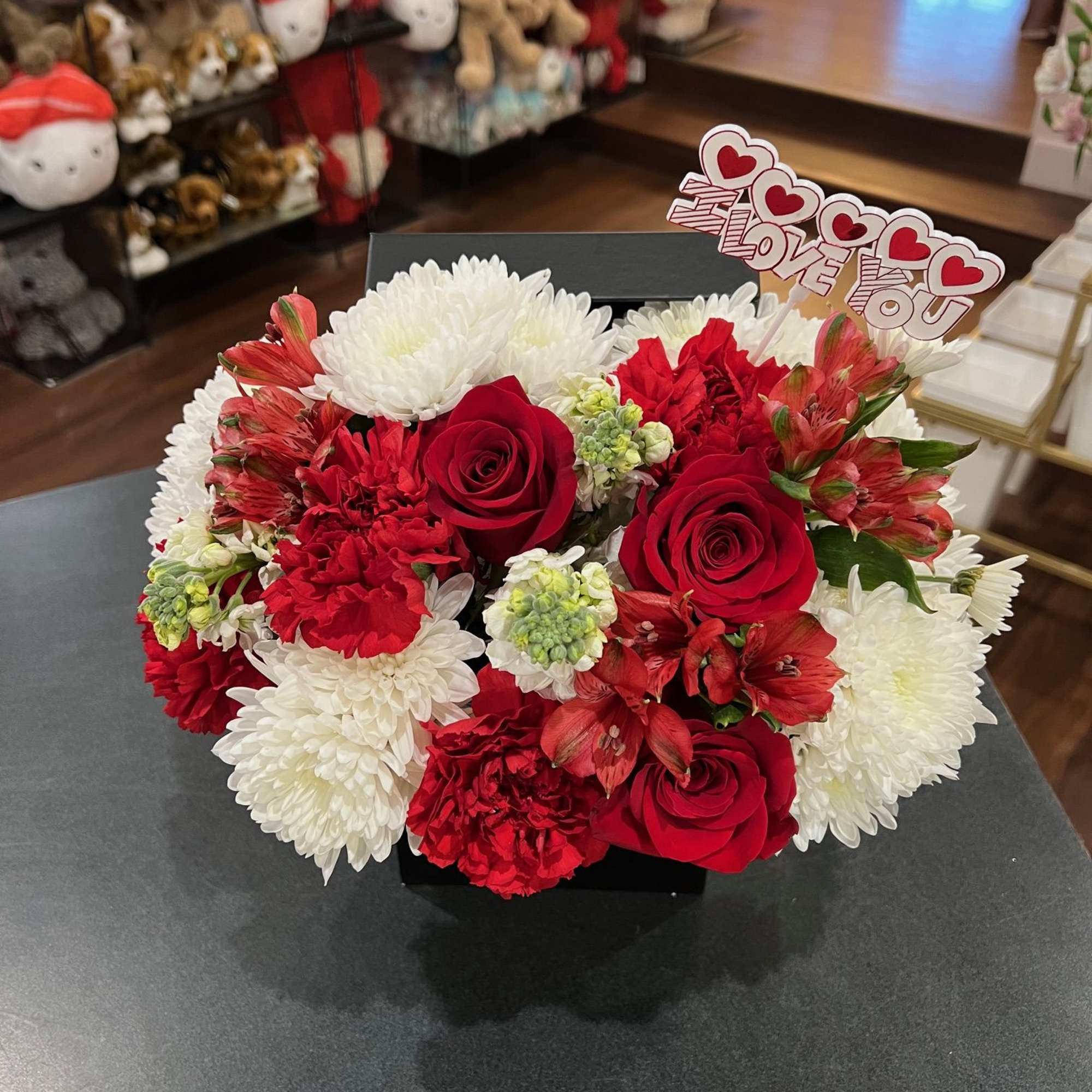 Red roses, red carnation, red alstromerias, white poms, and white stocks are
