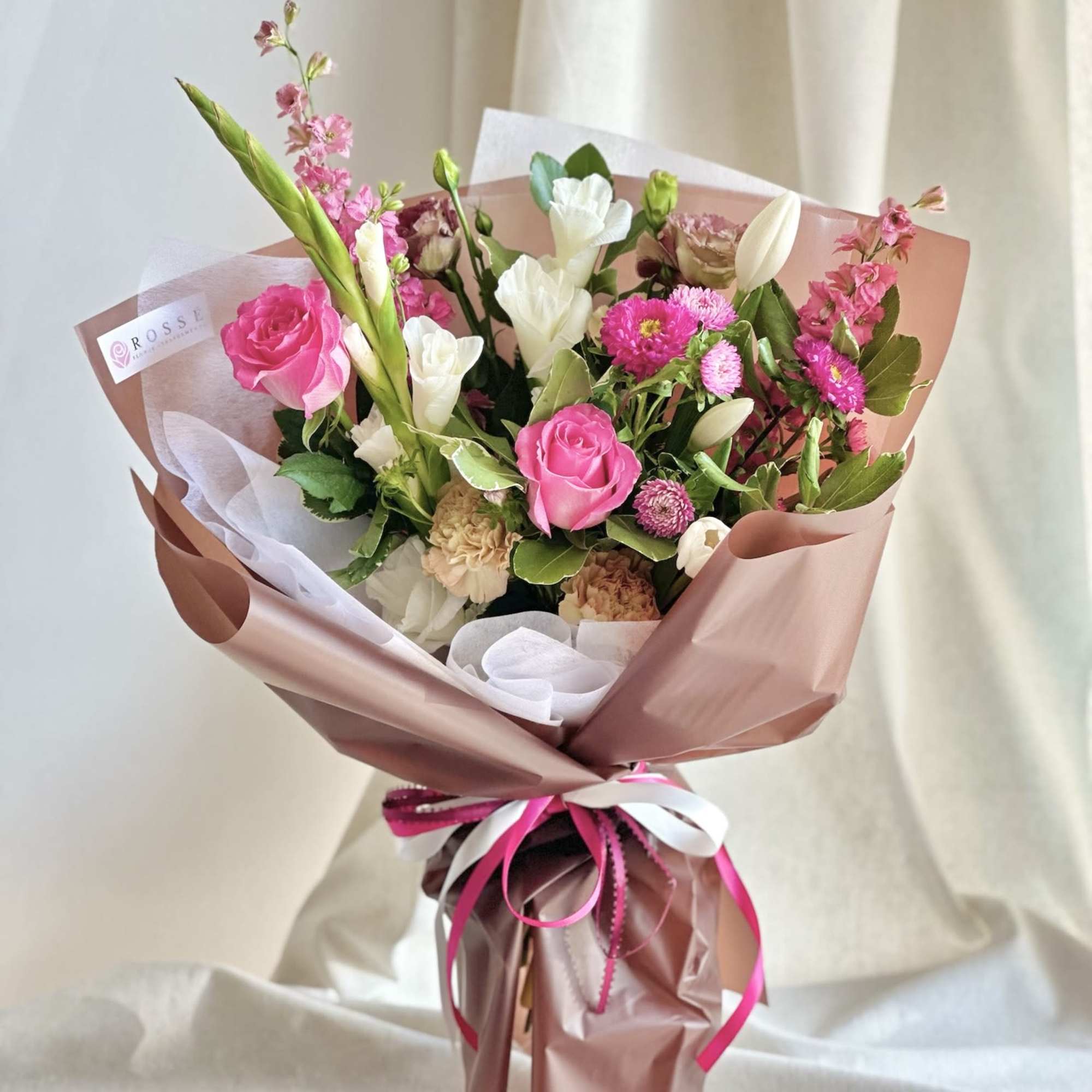 A front-facing bouquet with hot pink, white, and brown tones, wrapped in A front-facing bouquet with hot pink, white, and brown tones, wrapped in