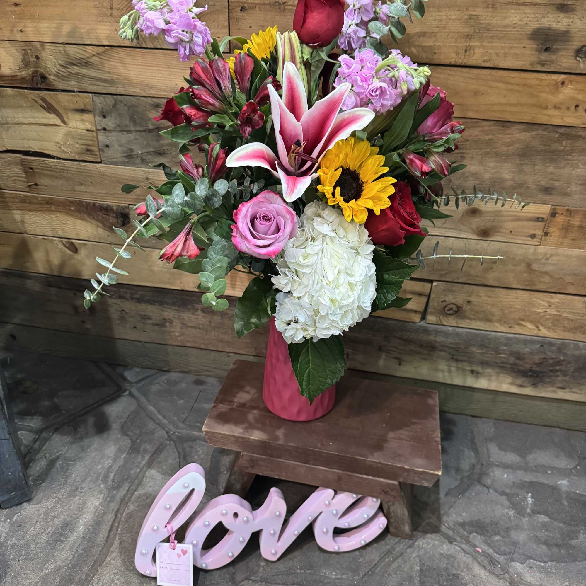 Beautiful pink vase with Ecuadorian roses, lily, and sunflowers with Valentine like