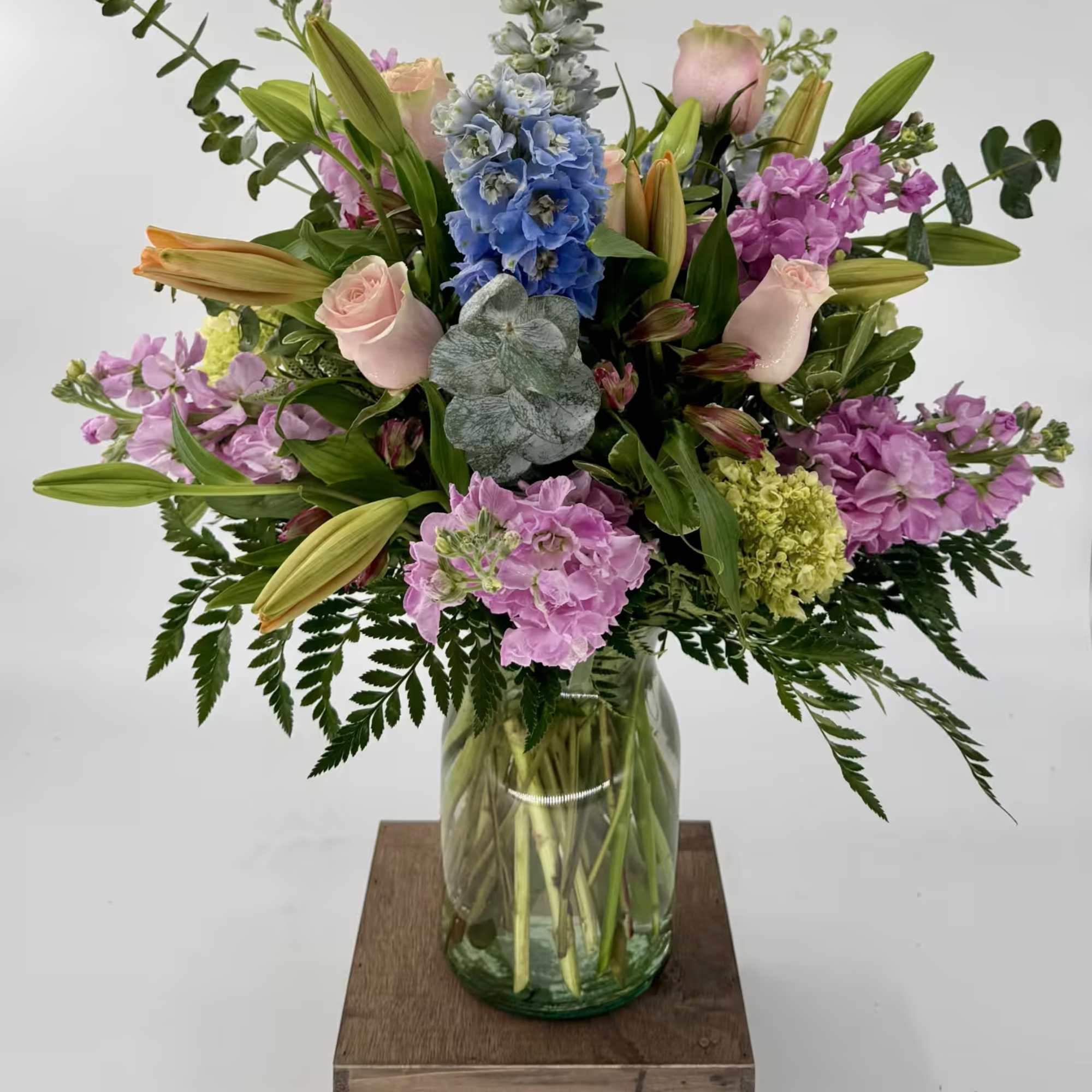 Brighten any space with this vibrant flower arrangement featuring blue Delphinium, pink