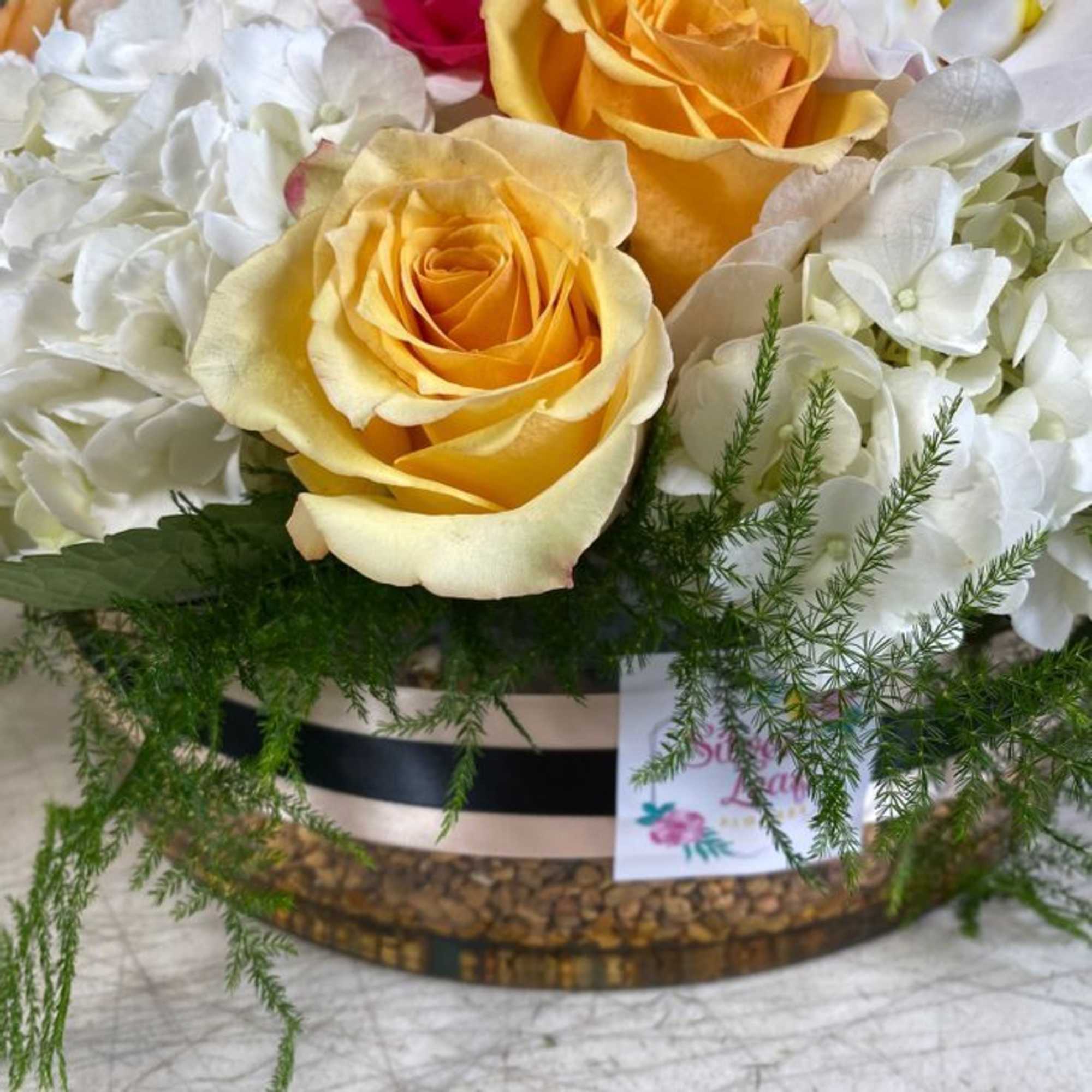 This arrangement includes roses, hydrangeas ,and other seasonal blooms. This is a