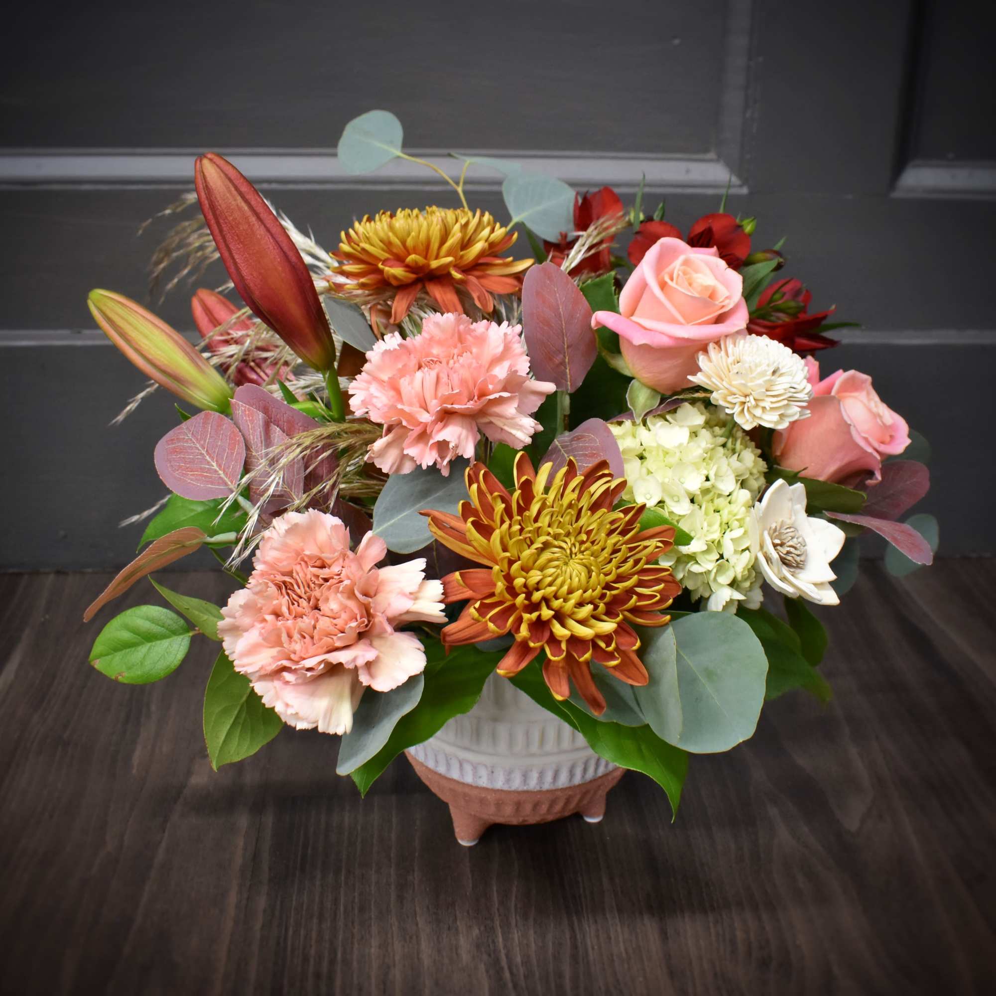 Beautiful lilies, fluffy mums and a wooden flower designed in a pottery Beautiful lilies, fluffy mums and a wooden flower designed in a pottery