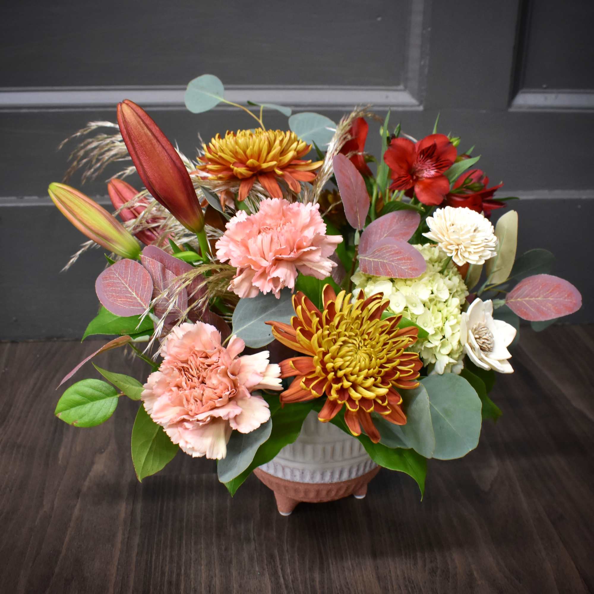 Beautiful lilies, fluffy mums and a wooden flower designed in a pottery Beautiful lilies, fluffy mums and a wooden flower designed in a pottery