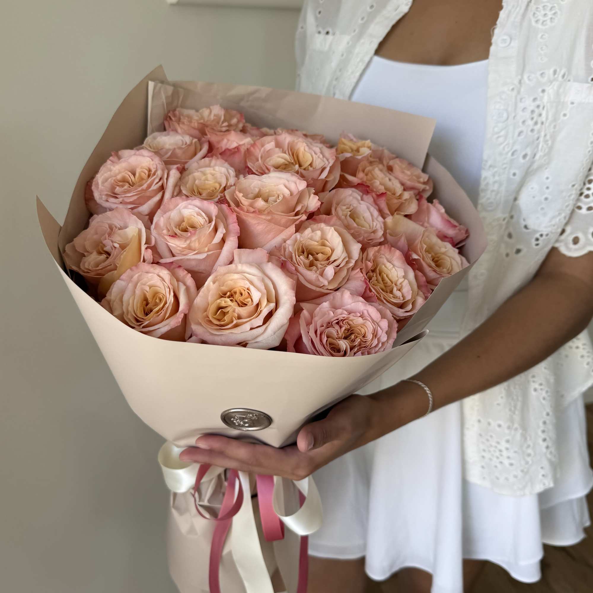 A fresh and elegant wrapped bouquet of roses with soft pink petals A fresh and elegant wrapped bouquet of roses with soft pink petals