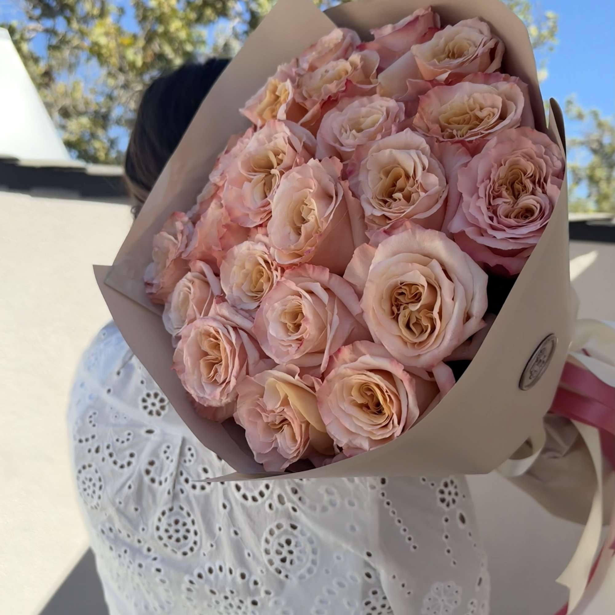 A fresh and elegant wrapped bouquet of roses with soft pink petals A fresh and elegant wrapped bouquet of roses with soft pink petals