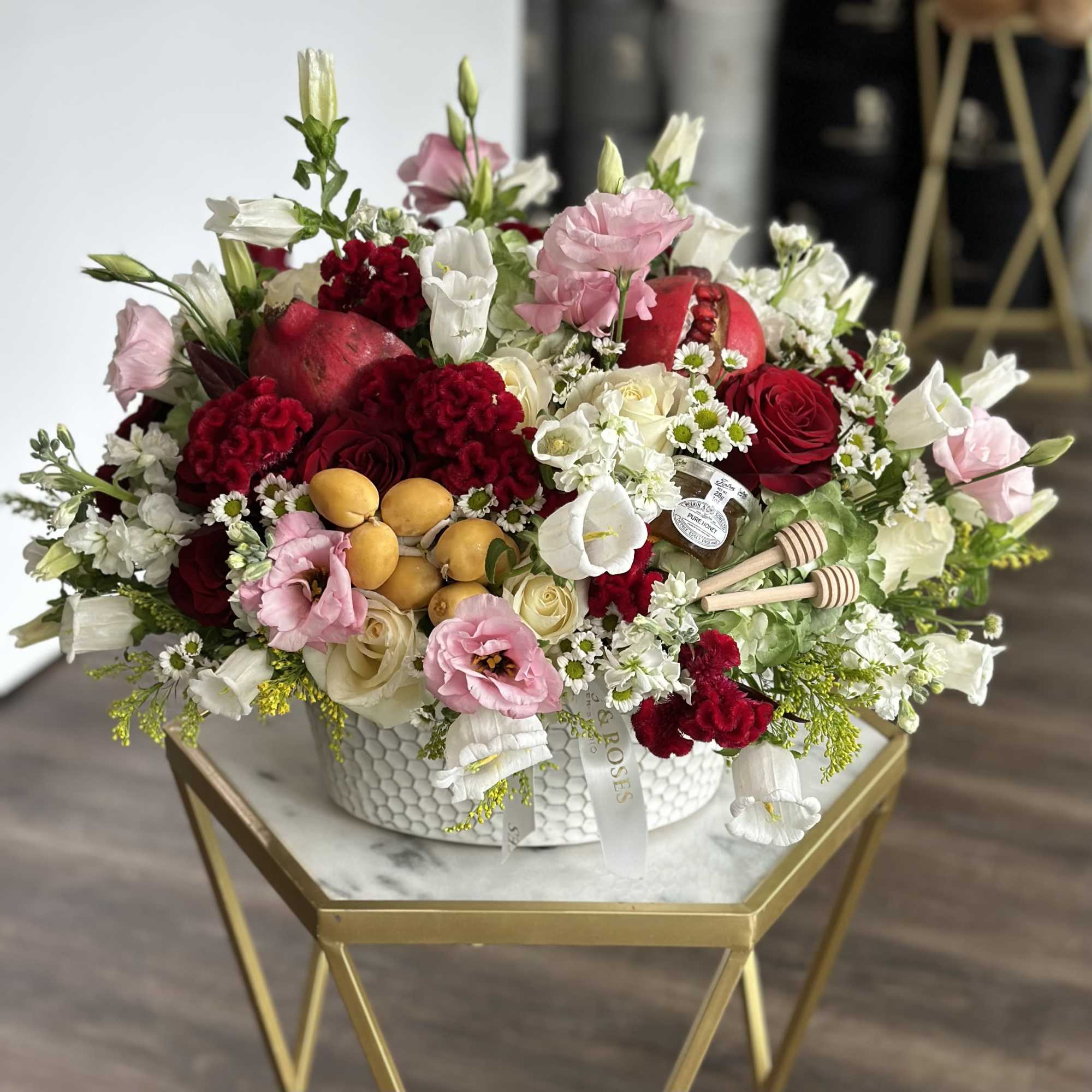 A festive Rosh Hashanah arrangement featuring vibrant pomegranates, golden honey jars, and