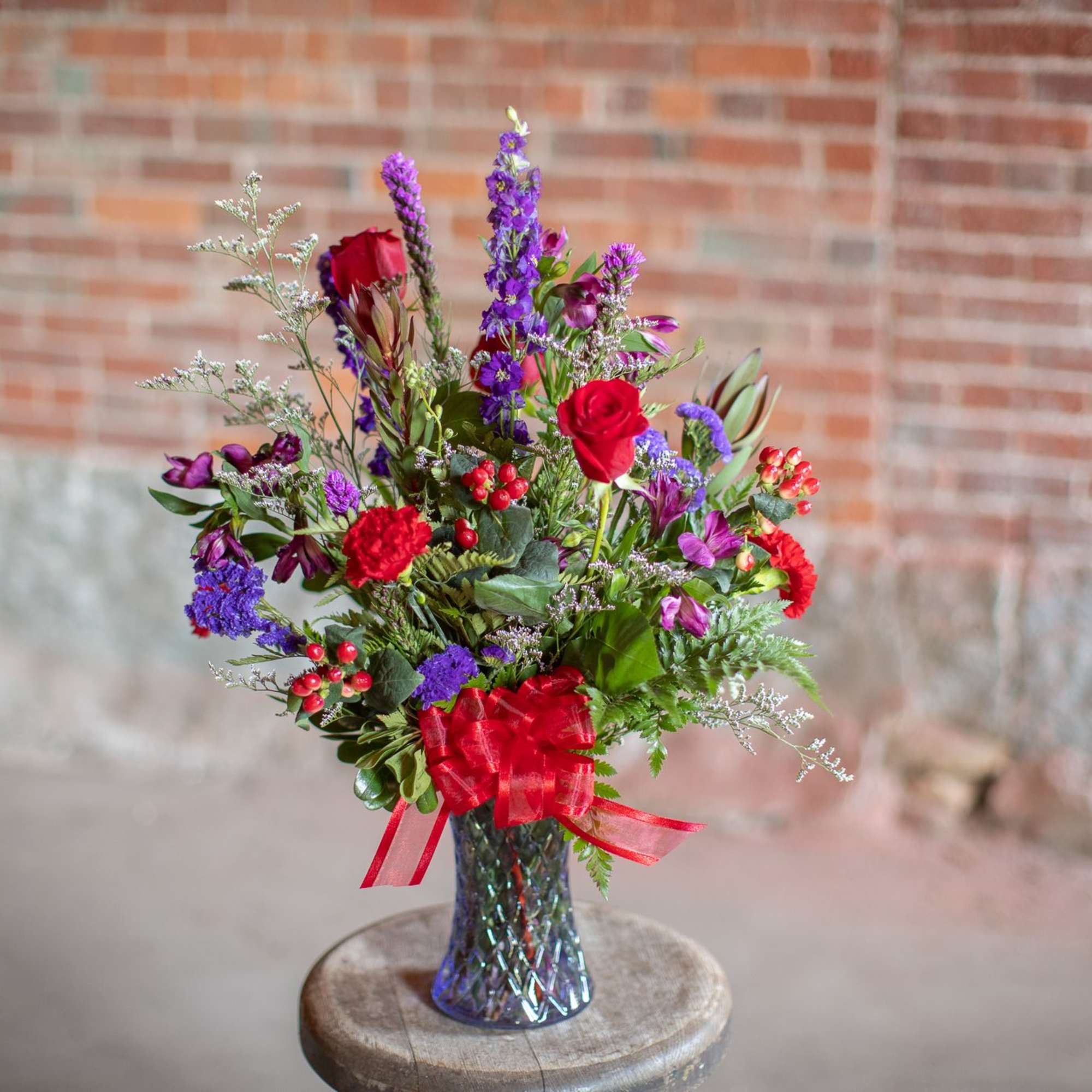 In a brilliant cut lavender vase are jewel toned beauties. Rich roses