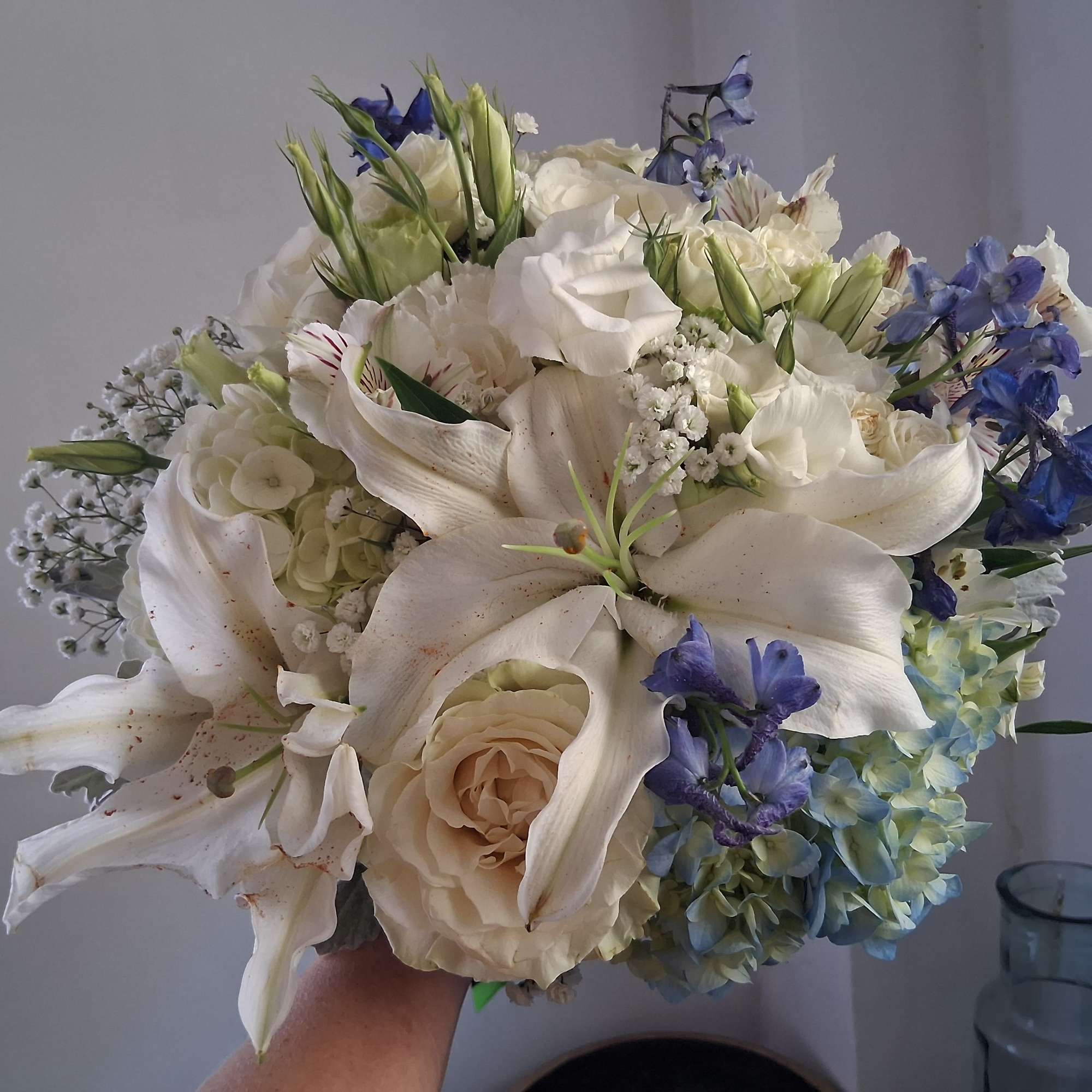 Magnificent white oriental lily, garden roses, white lisiantus, blue hydrangea and delphinium