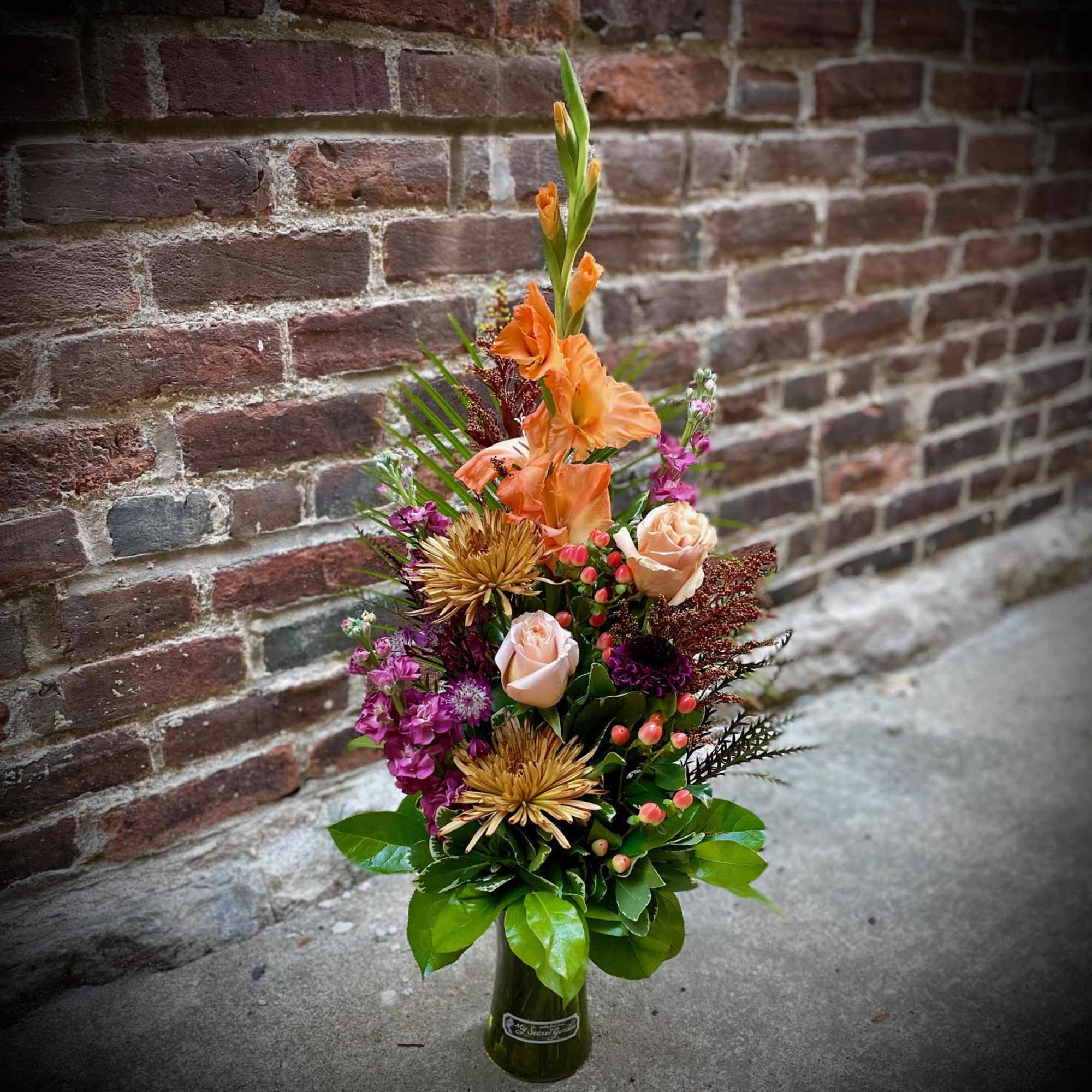 The Blissful Autumn is artfully arranged with roses, spider mums, stock, gladiolas
