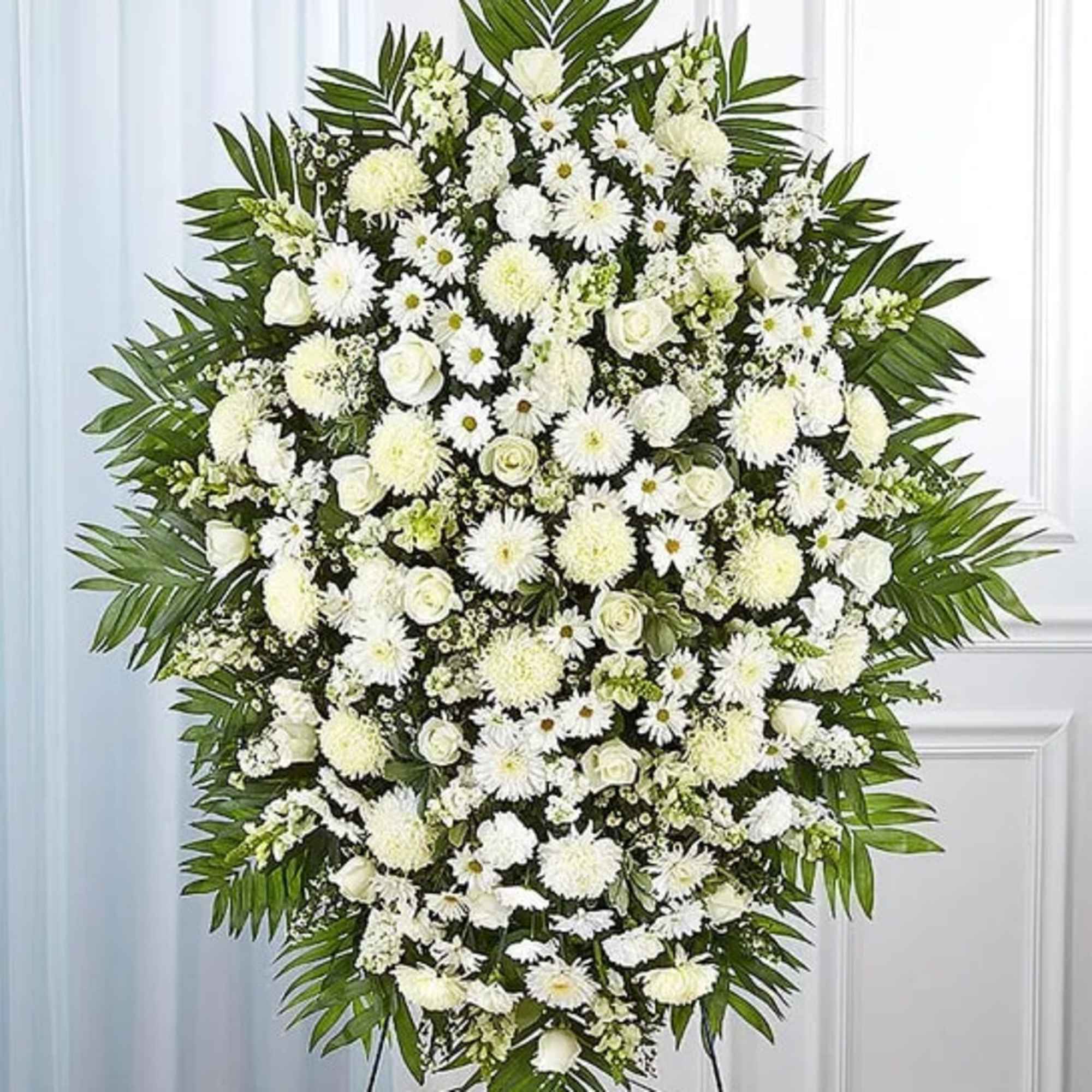 This all-white standing spray arrangement with roses, football mums, cremones, stock, snapdragons