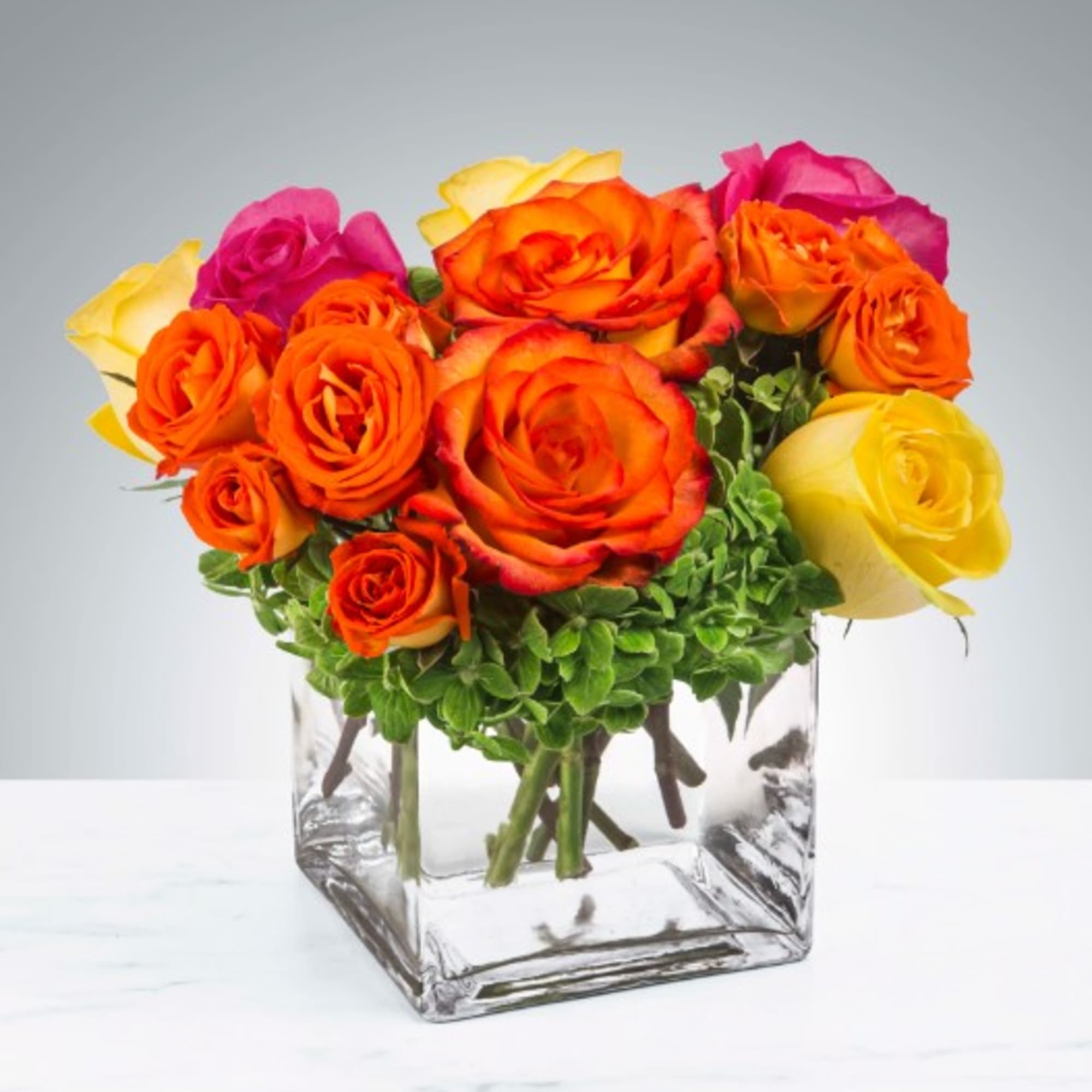 Pink, yellow and orange roses come together with green hydrangea for a