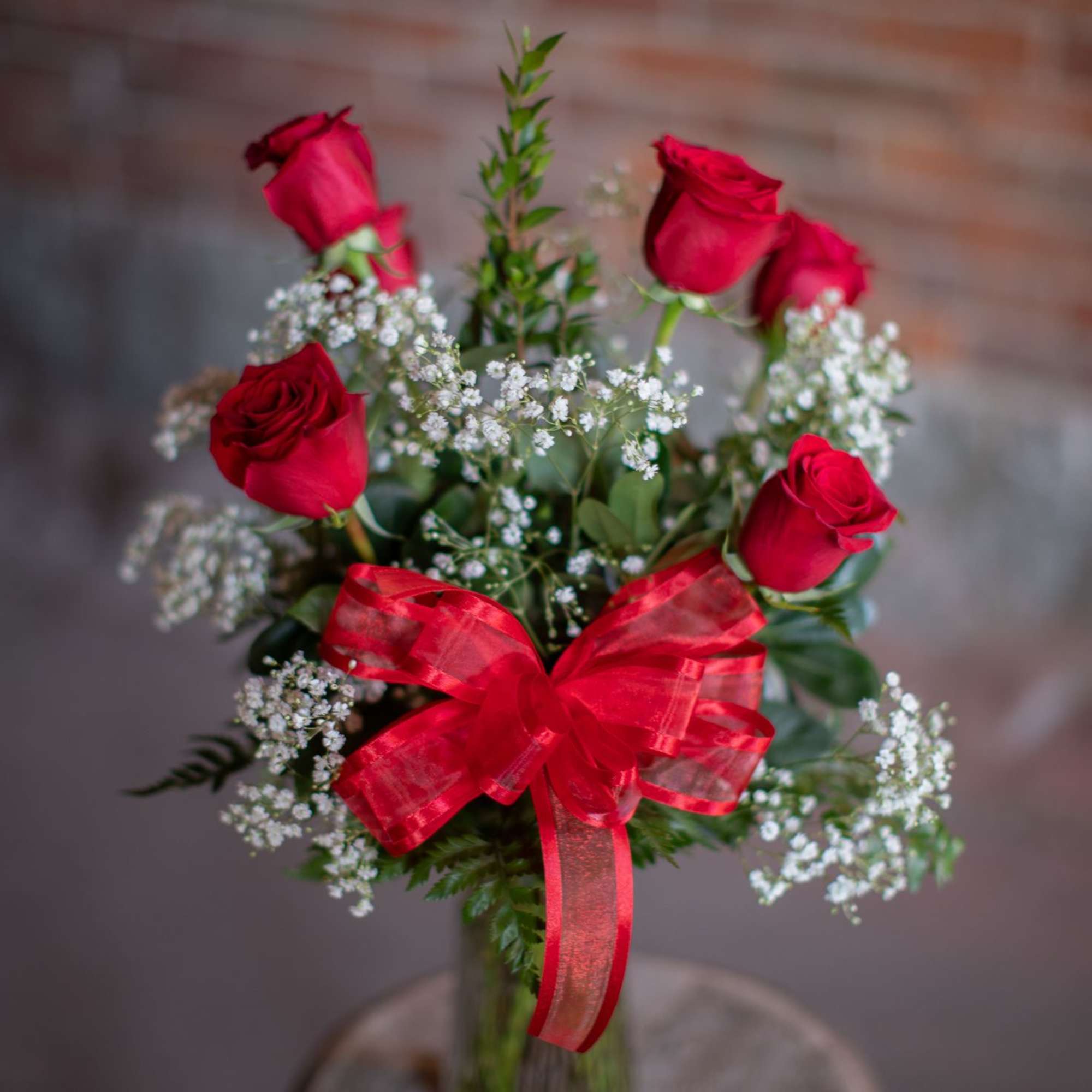 6 premium AAA grade red roses beautifully arranged in a clear vase