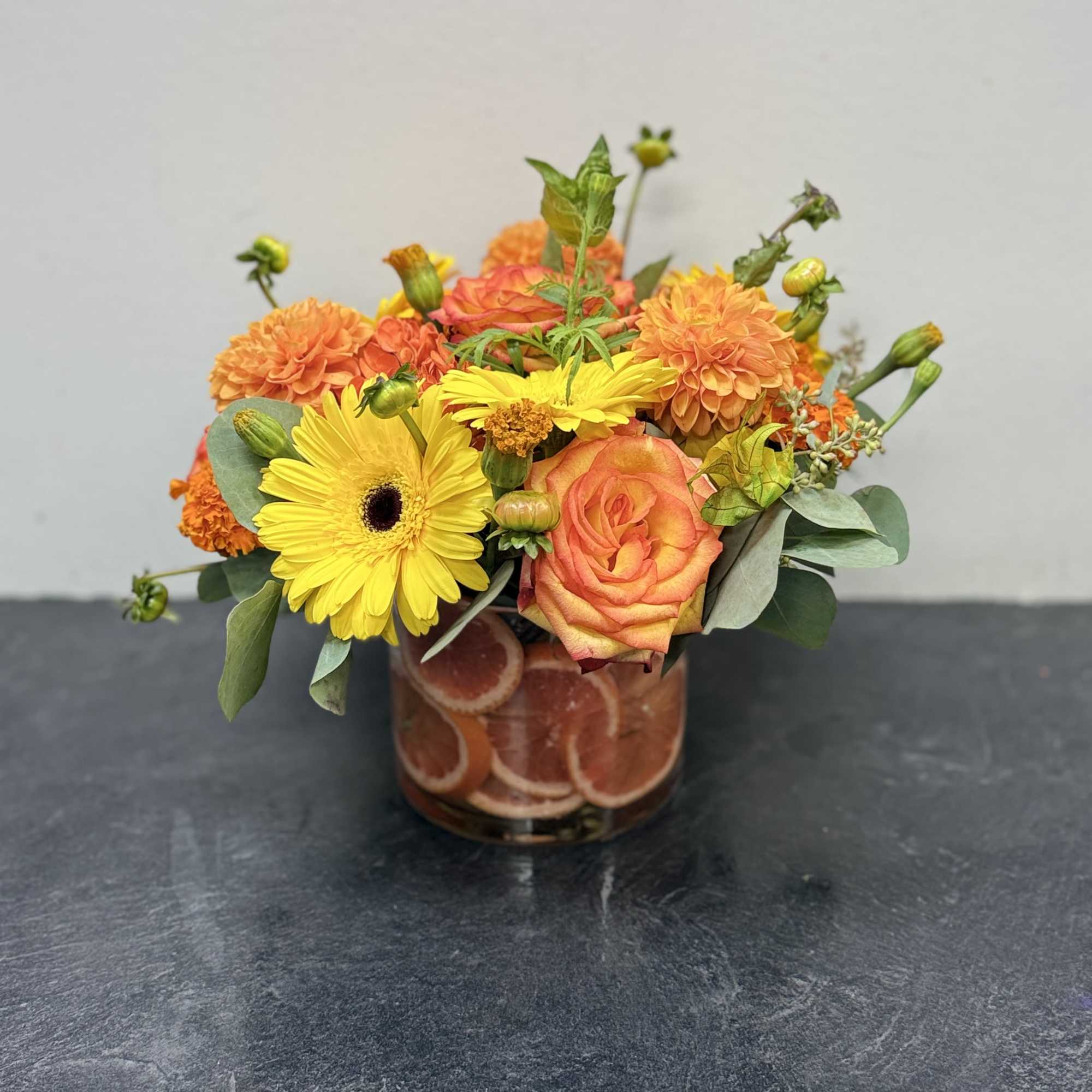 Bright and cheerful, this vibrant arrangement bursts with the warm hues of