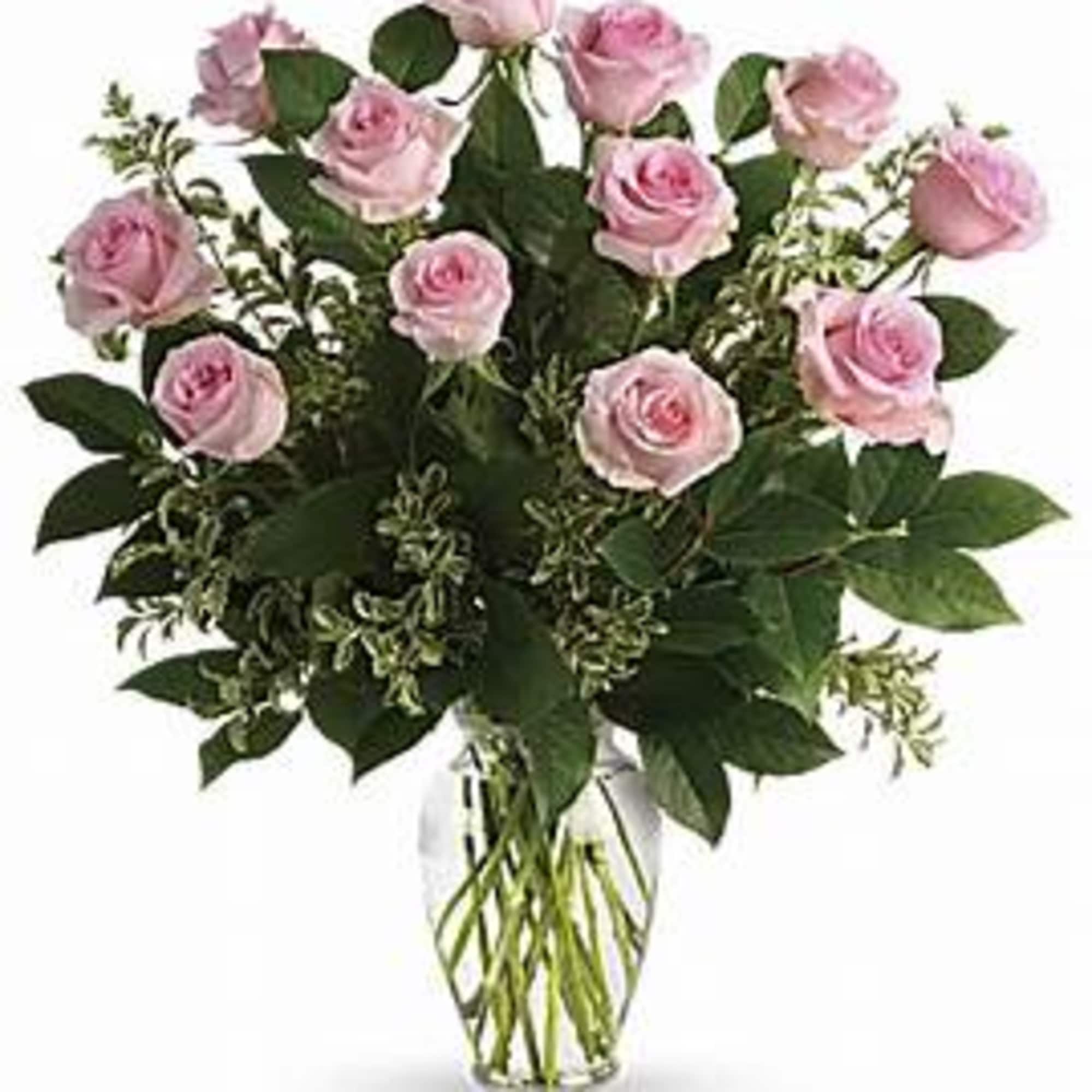 Dozen pink roses in a clear vase with beautiful greens. This is Dozen pink roses in a clear vase with beautiful greens. This is