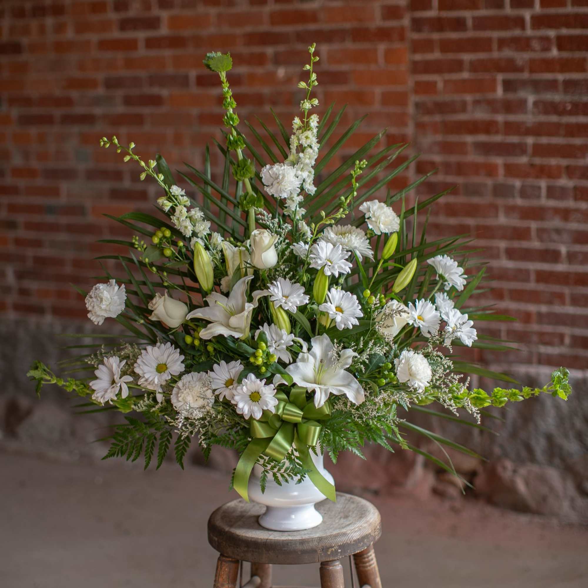 Traditional all white one sided funeral urn arrangement. Floral selections will be