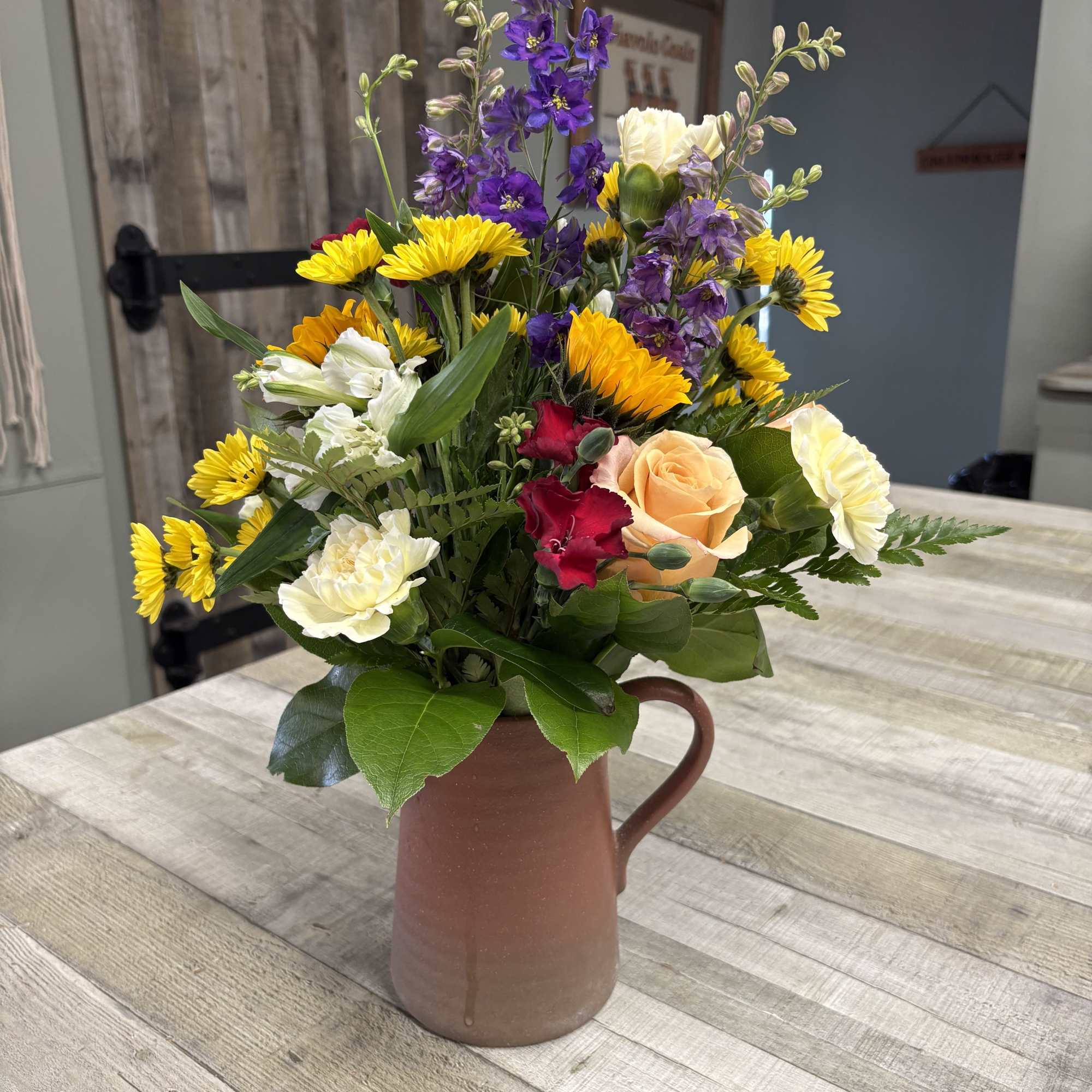 A reusable stoneware pitcher filled with seasonal blooms. This keepsake container is