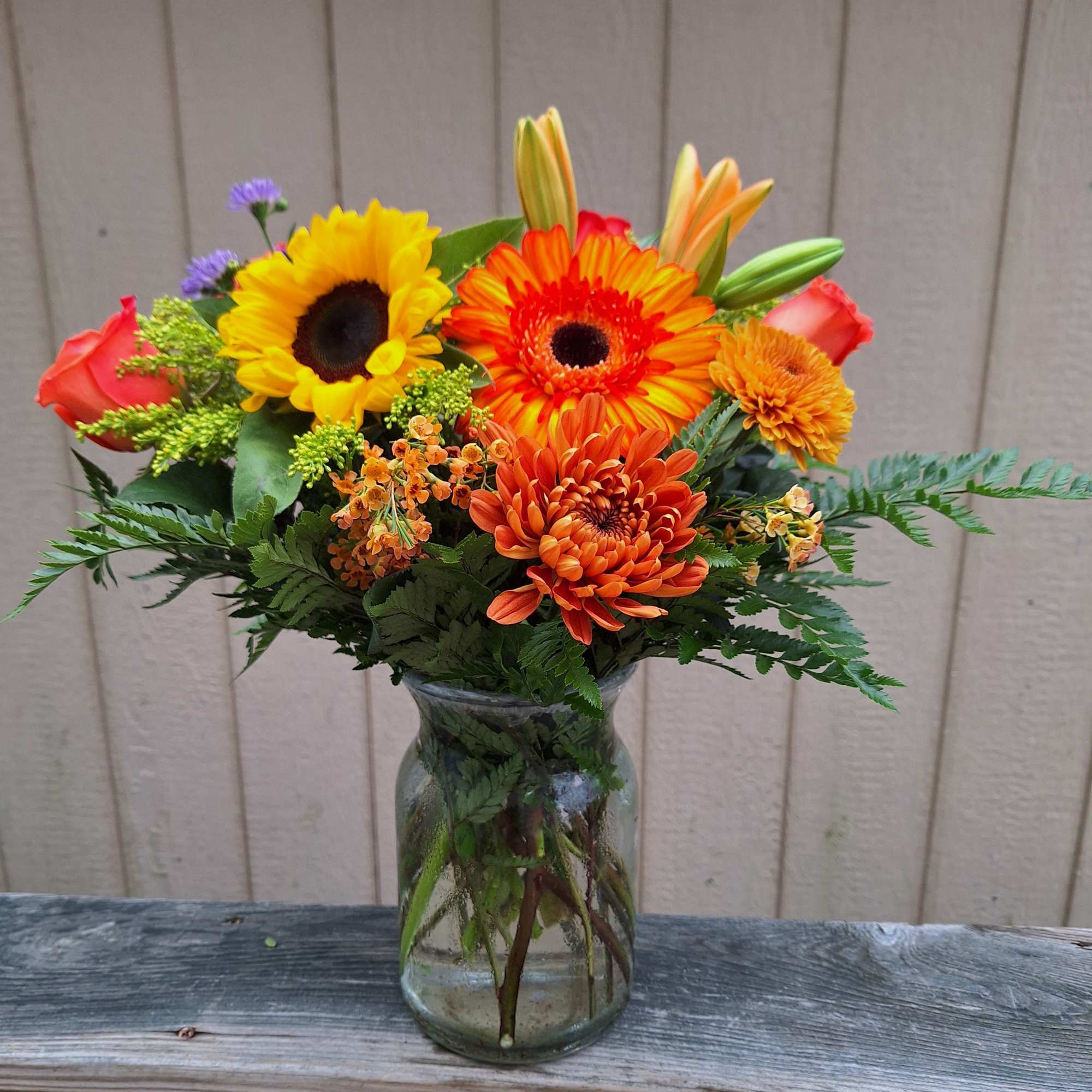 Orange gerberas,  sunflowers, bronze mums, orange lilies, orange roses, orange wax