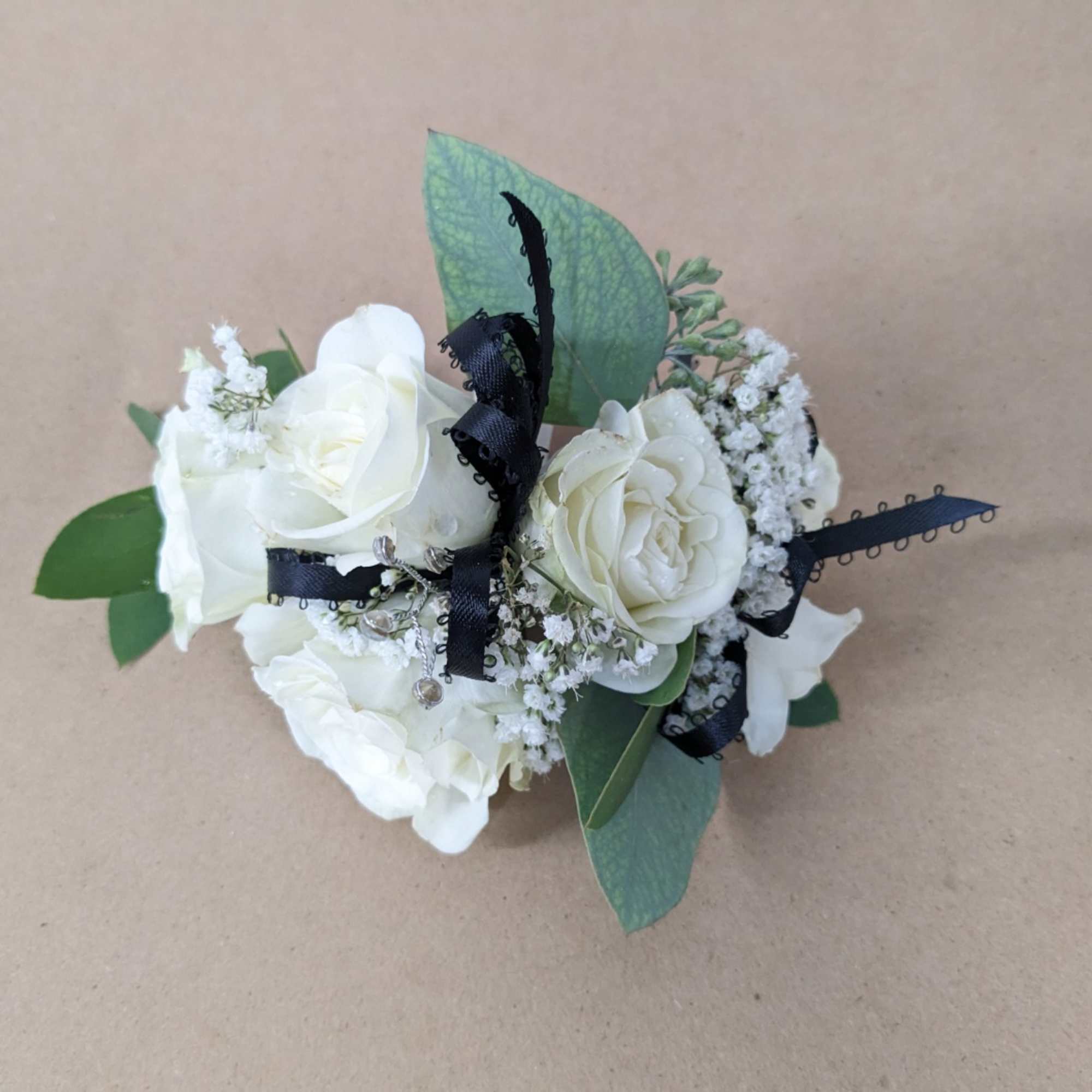 A classic white corsage with some ribbons, this wrist arrangement looks good