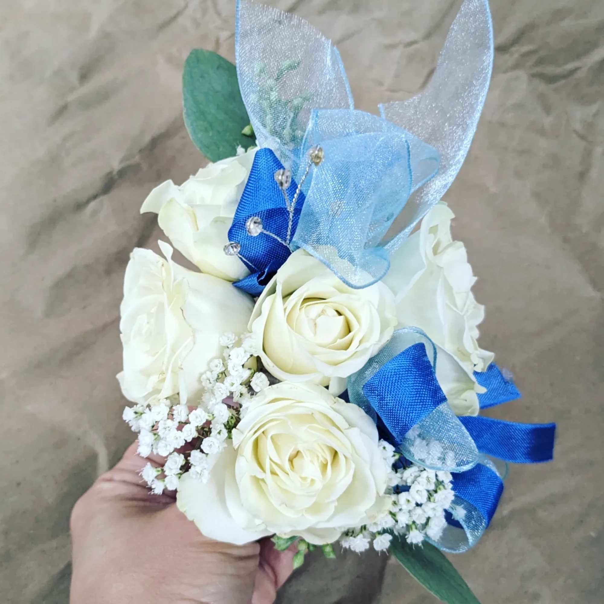 A classic white corsage with some ribbons, this wrist arrangement looks good