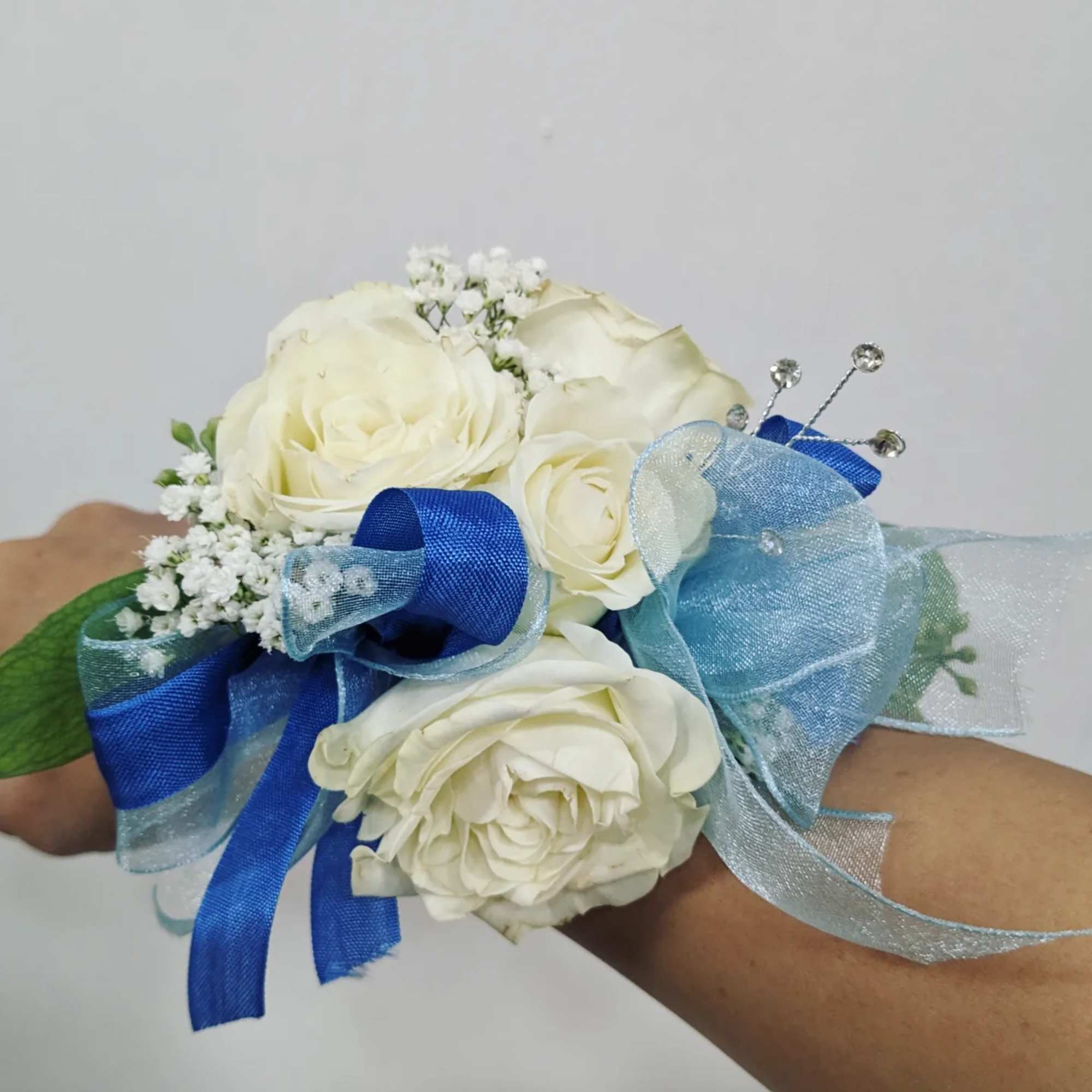 A classic white corsage with some ribbons, this wrist arrangement looks good