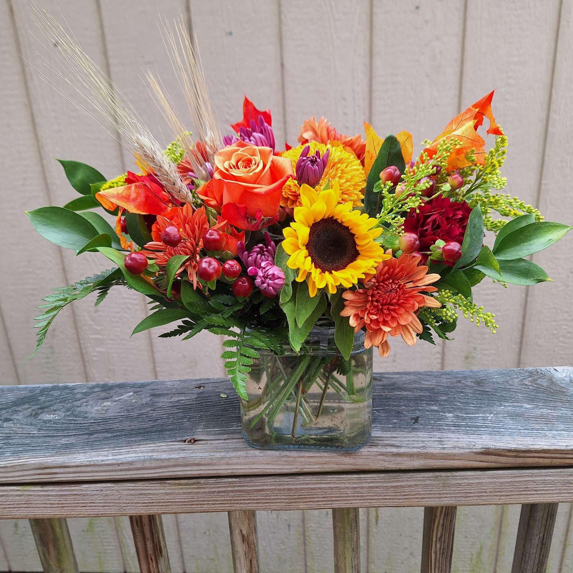 Brilliant yellow sunflowers, orange roses, gold and bronze chrysanthemums, burgandy carnations, lavender
