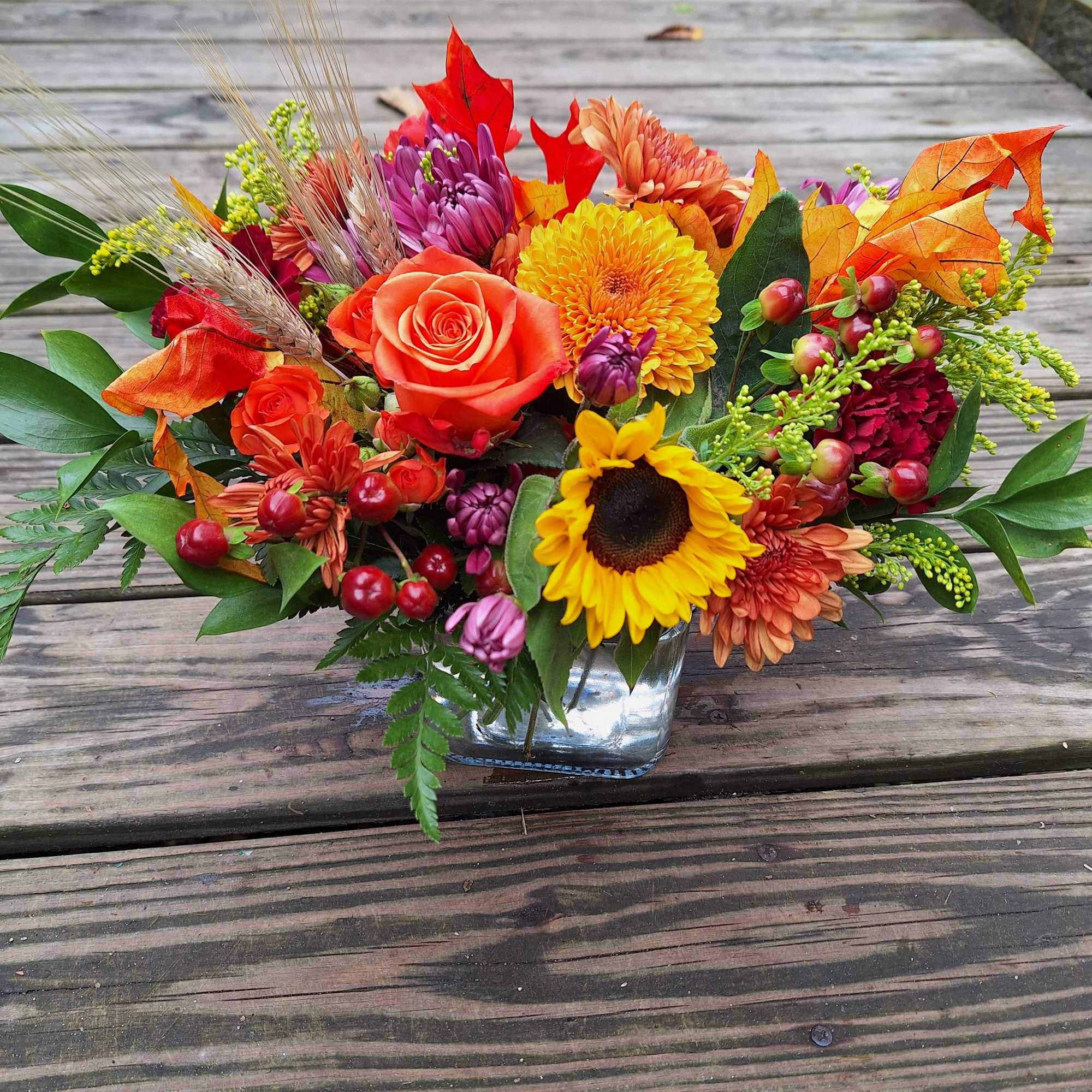 Brilliant yellow sunflowers, orange roses, gold and bronze chrysanthemums, burgandy carnations, lavender