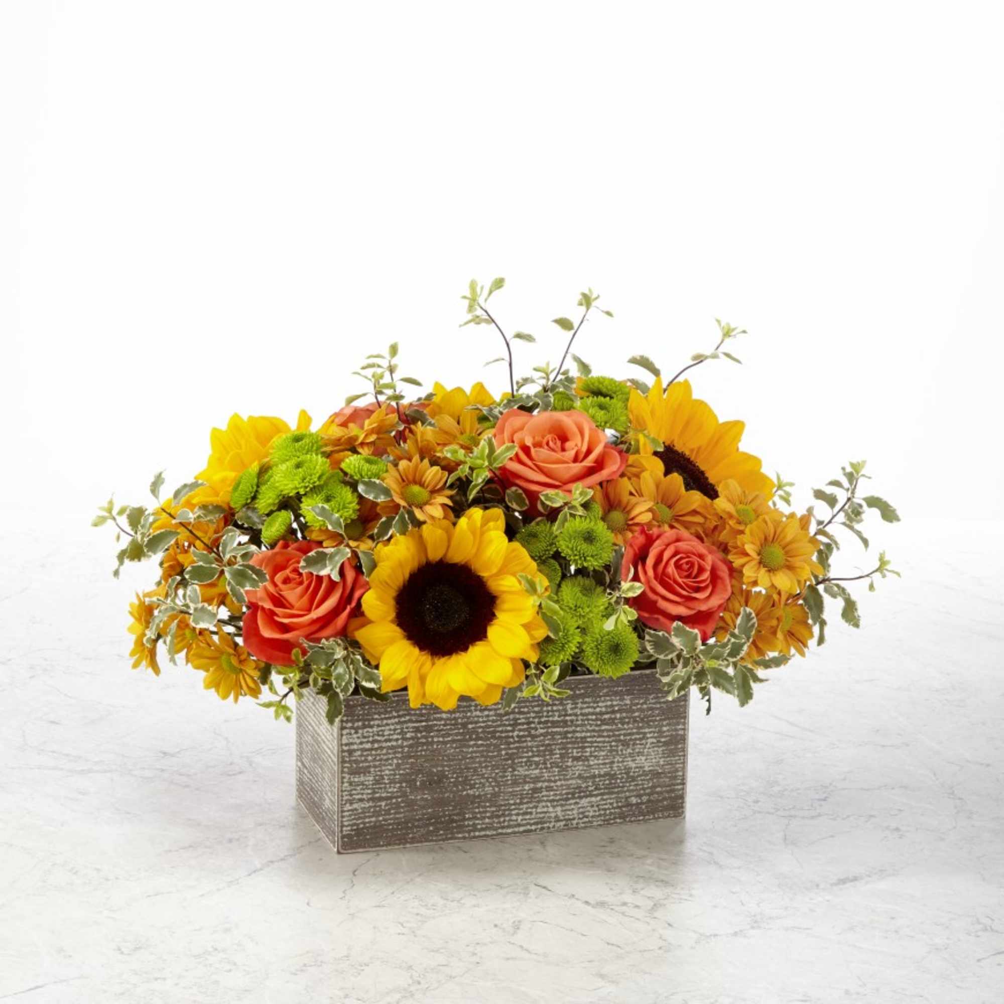 Brightly colored roses and sunflowers arranged in a rustic box make a