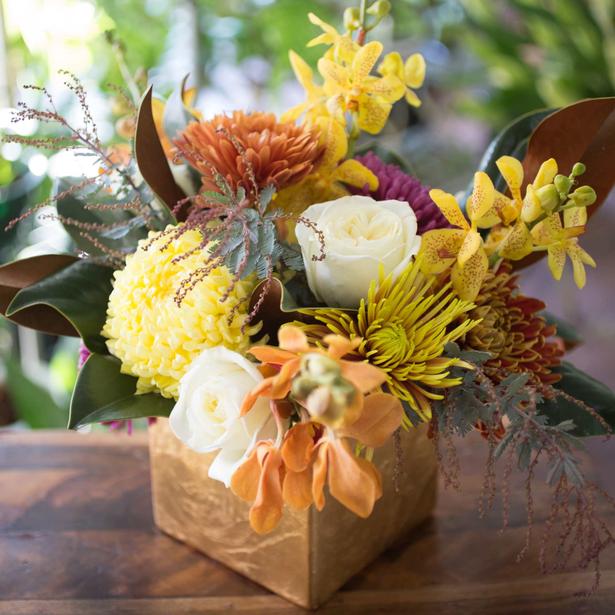 Magnolia leaves, Chrysanthemums, Roses and Orchids create the perfect table centerpiece, arranged