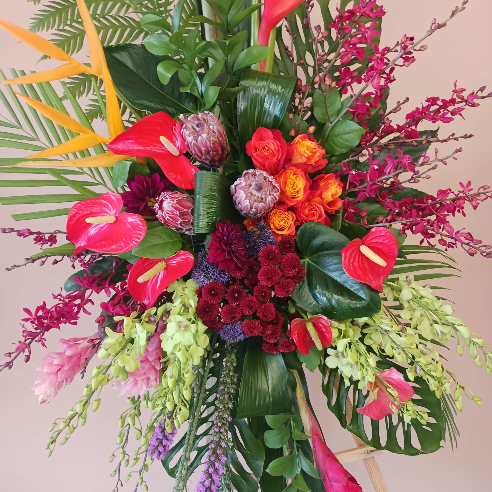 Standing spray on a easel with bright tropical flowers